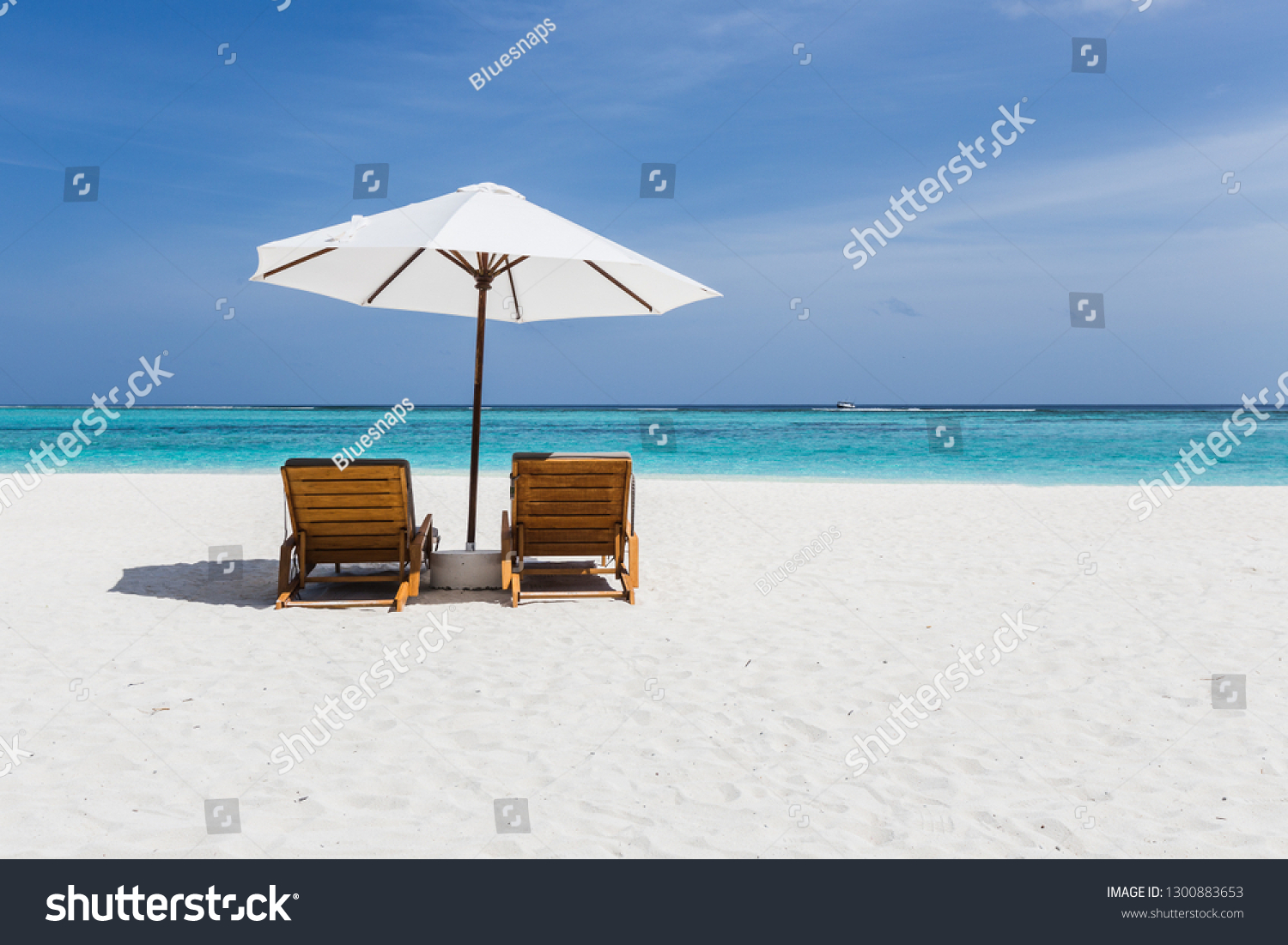 Beach chairs with a view of clear blue water in the Maldives #1300883653