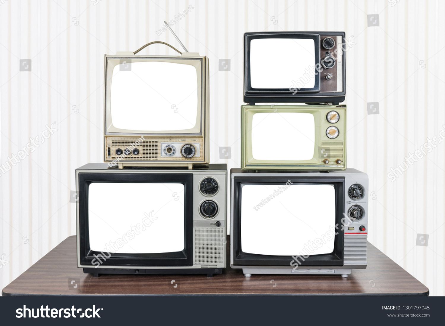 Five vintage televisions on old wood table with cut out screens. #1301797045