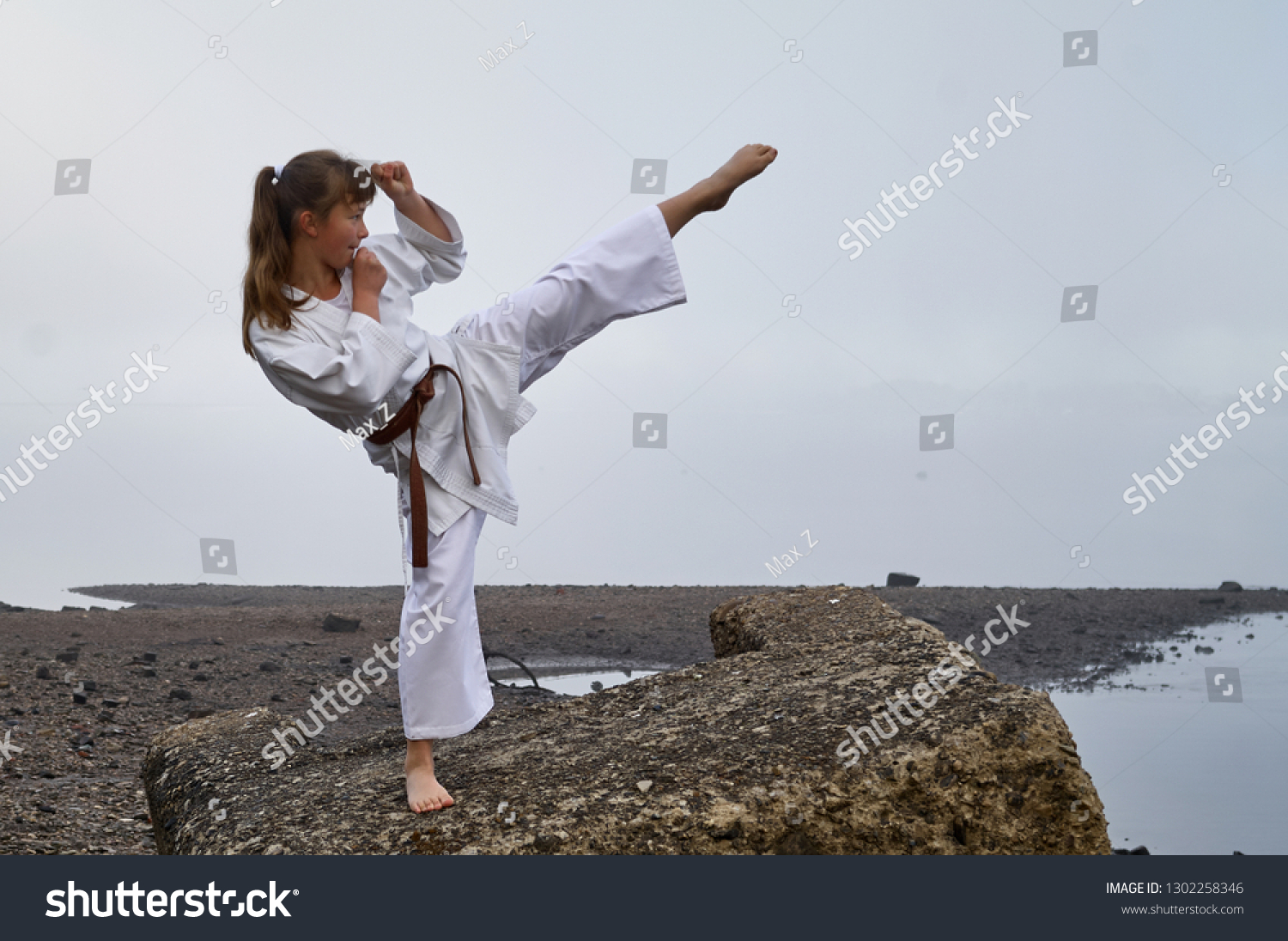 Young Woman in Kimono practicing karate, Japanese martial arts on river coast. Early foggy morning #1302258346