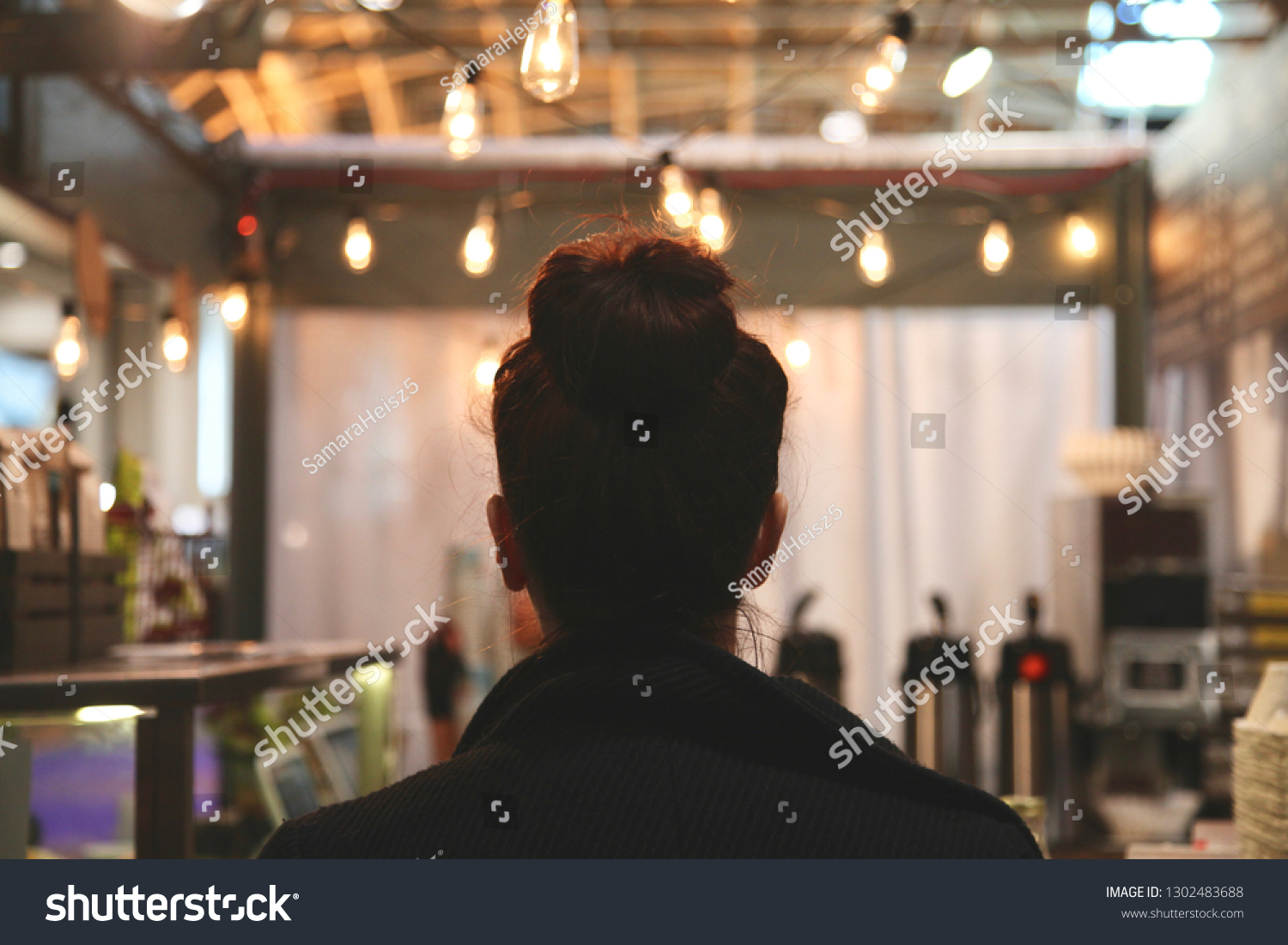 Woman waiting for her coffee at a cafe with string lights  #1302483688