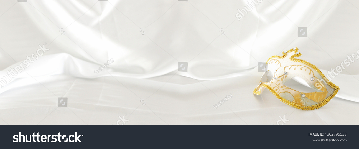 Banner of elegant and delicate gold venetian mask over white silk background #1302795538
