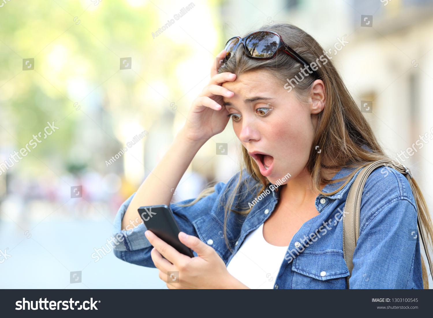 Shocked teenage girl checking smart phone discovering mistake content in the street #1303100545