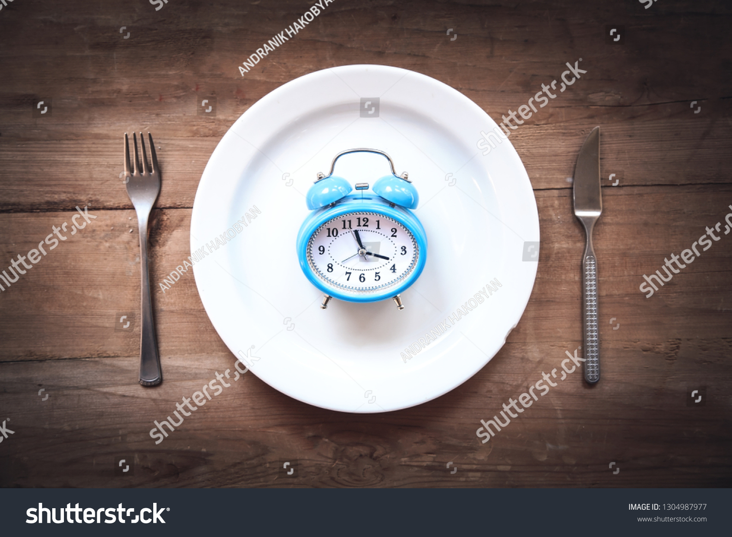 Alarm clock with fork and knife on the table. Time to eat #1304987977