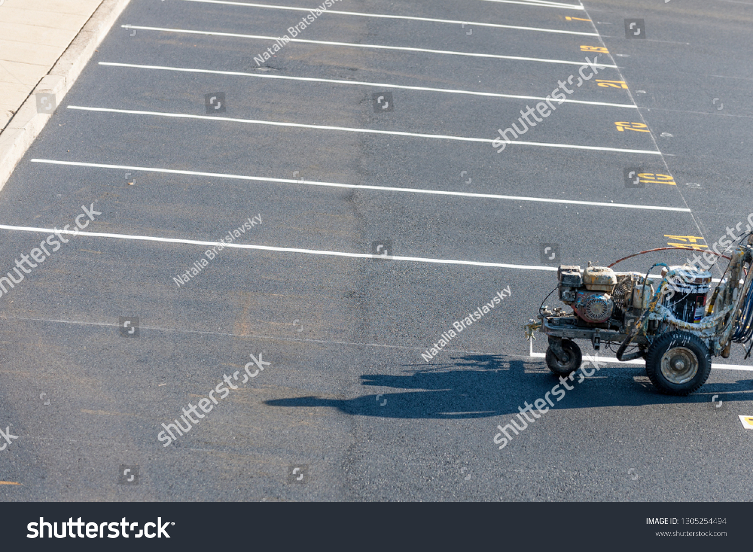 Worker with a striping mashing painting fresh lines in development parking lot, USA #1305254494