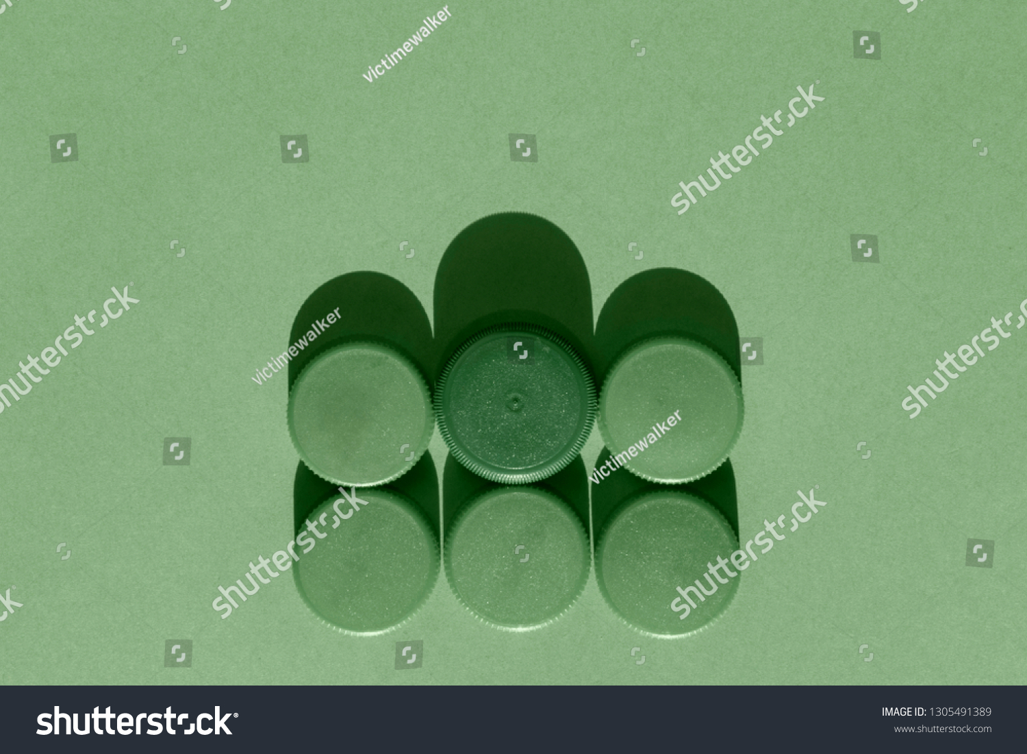 Six green plastic bottle caps on a green background, the round caps are in two rows , monochromatic effect #1305491389