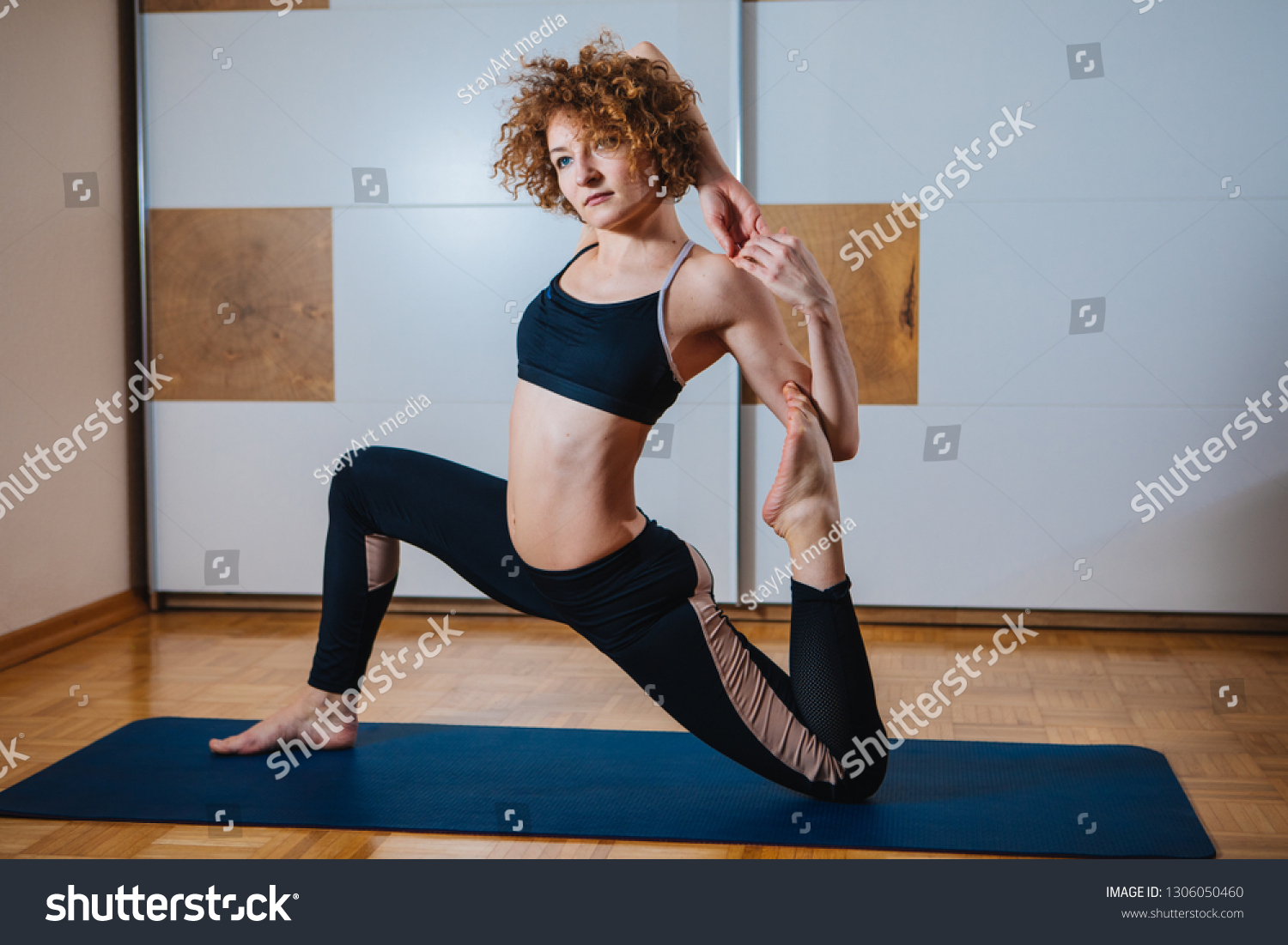 Sporty beautiful young woman practicing yoga, doing Splits Exercise, Monkey God Pose, stretching the thighs, hamstrings, groins, working out wearing black sport #1306050460