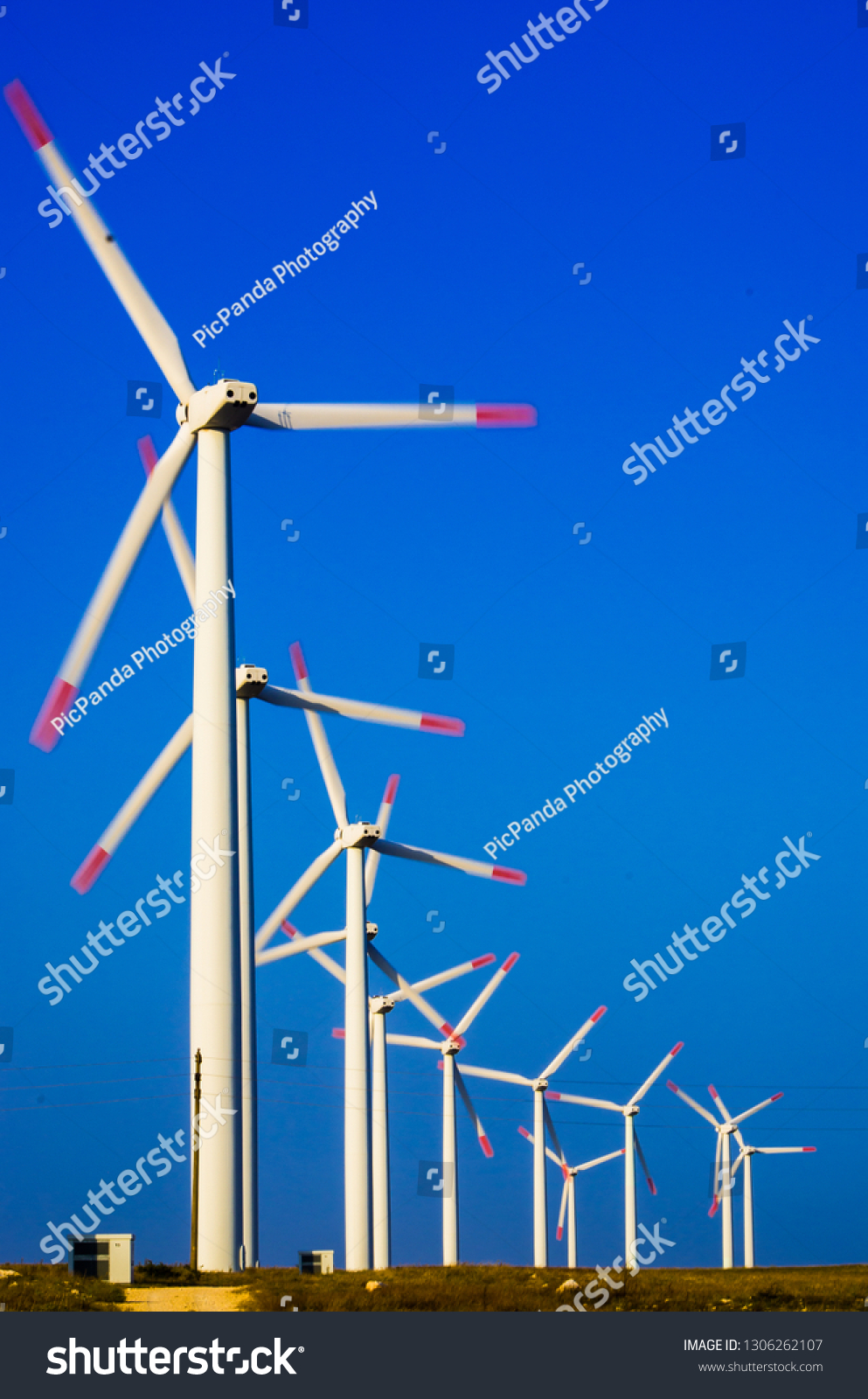 A row of rotating electric windmills. White wind turbines on a blue contrasty sky. #1306262107