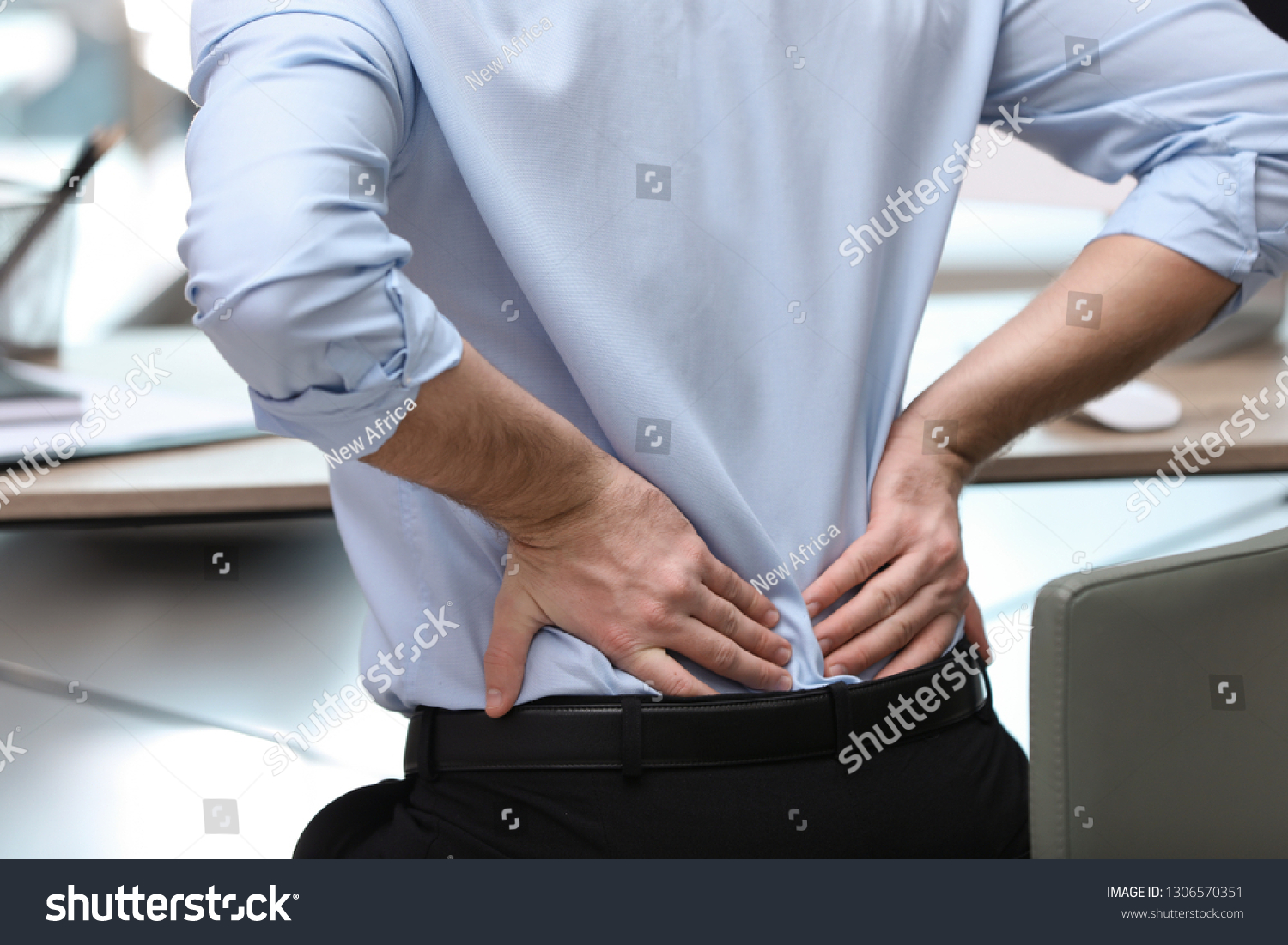 Businessman suffering from back pain at workplace, closeup #1306570351