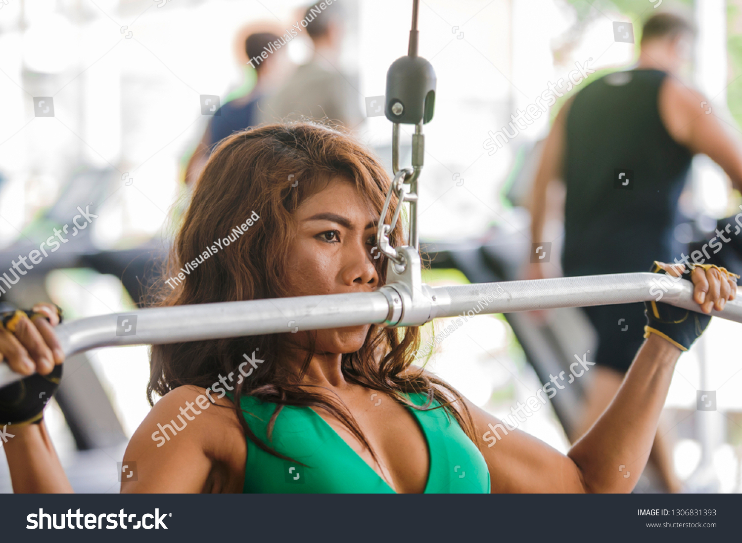 young athletic and determined Asian Indonesian woman working hard on weights using chest bodybuilding gym machine at fitness club in determination and healthy lifestyle concept #1306831393