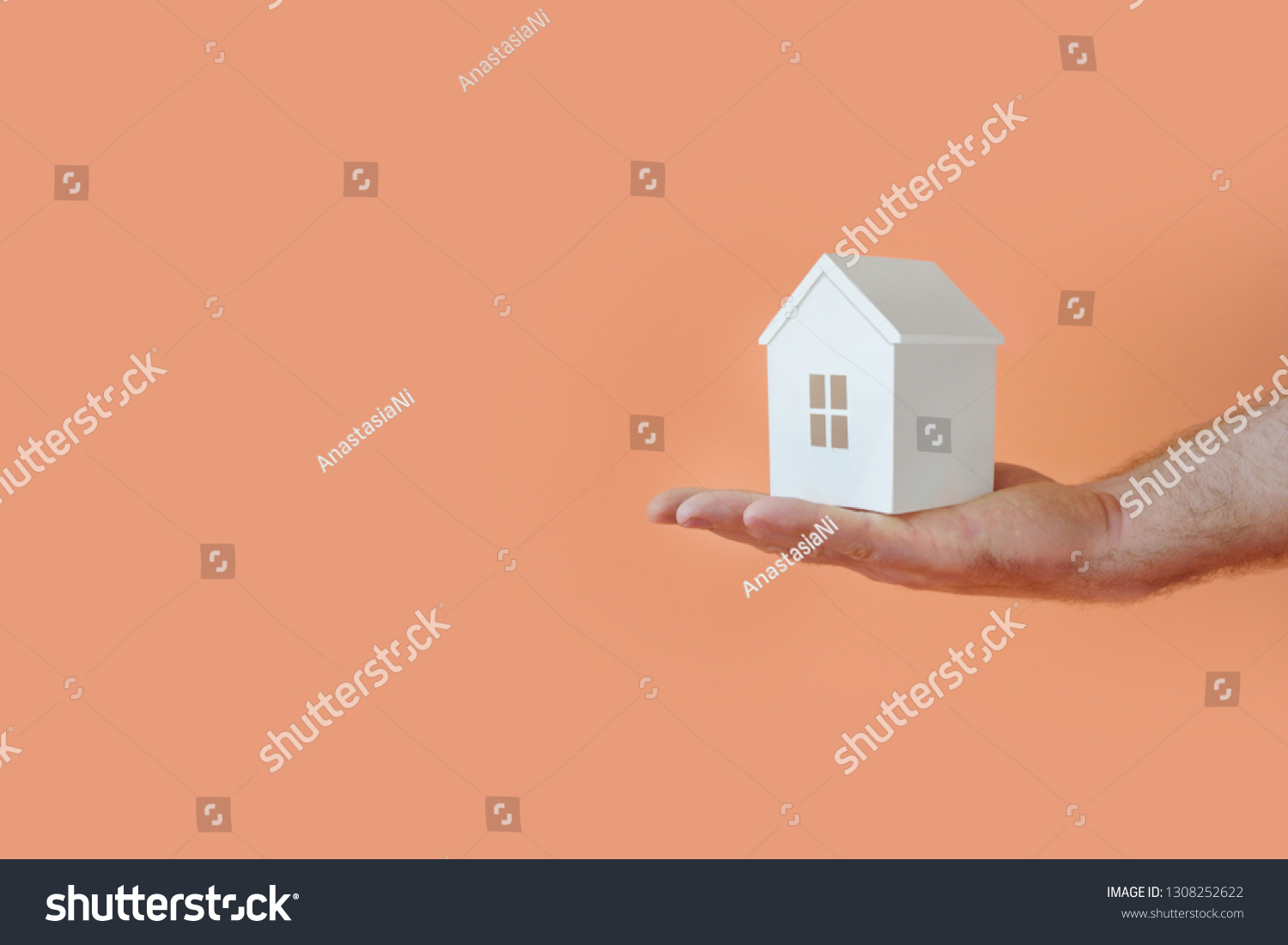 Male hand with model house. Copy space. Living coral #1308252622