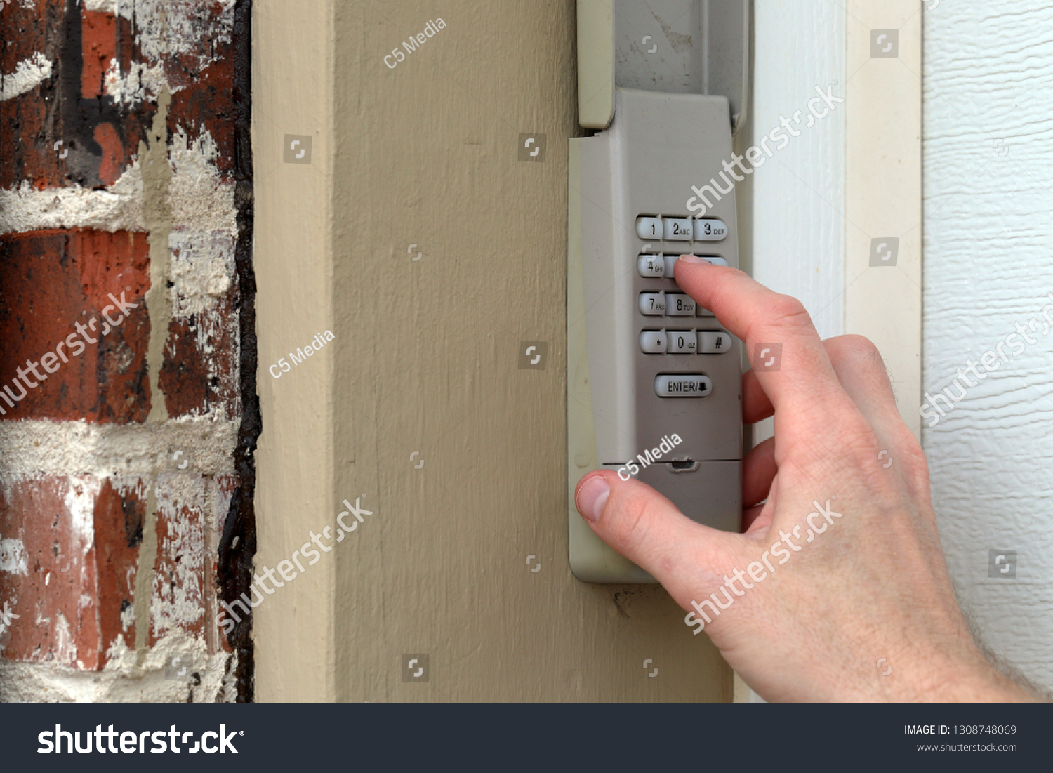 finger entering code on Keypad used on a garage door entrance to a home - security keypad - security code #1308748069