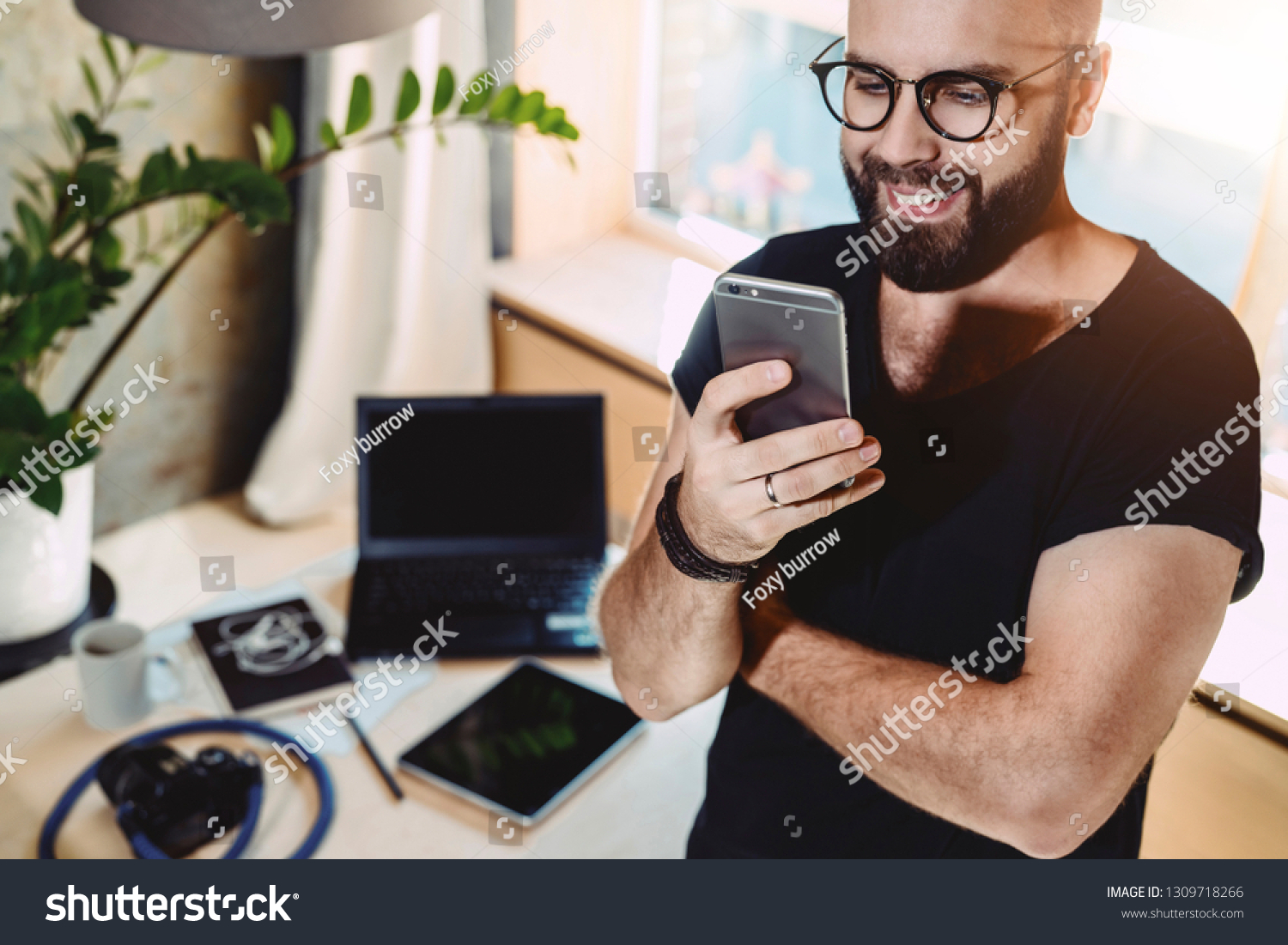 Portrait smiling handsome man reading text message, standing indoors.Businessman sends messages.Stylish brunette hipster uses mobile phone at home. Guy is chatting online. Man browsing social network. #1309718266