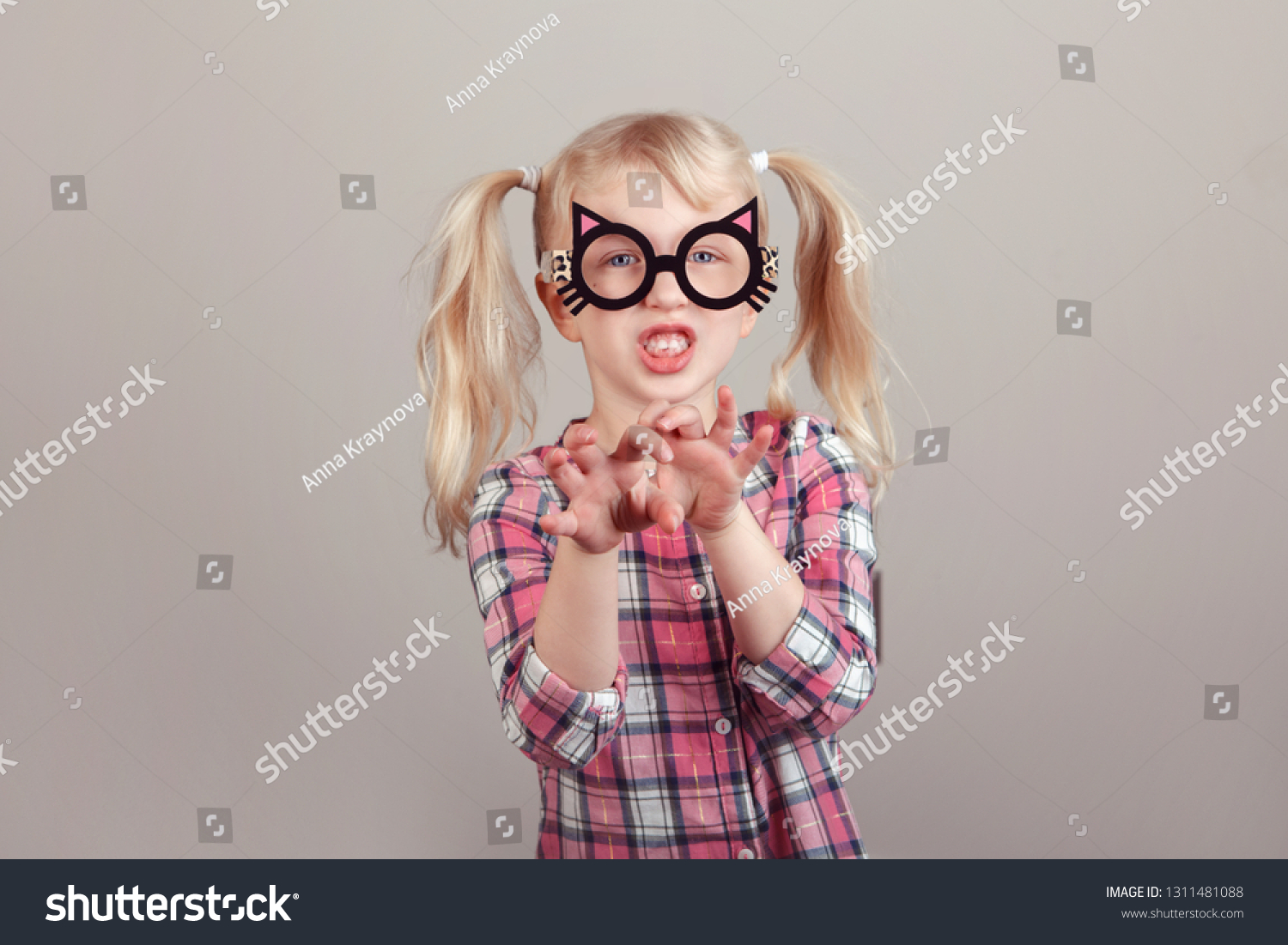 Closeup portrait of cute adorable blonde Caucasian preschool girl wearing funny cat glasses and playing, acting, making faces. Kid expressing emotions. April fool's day concept. #1311481088