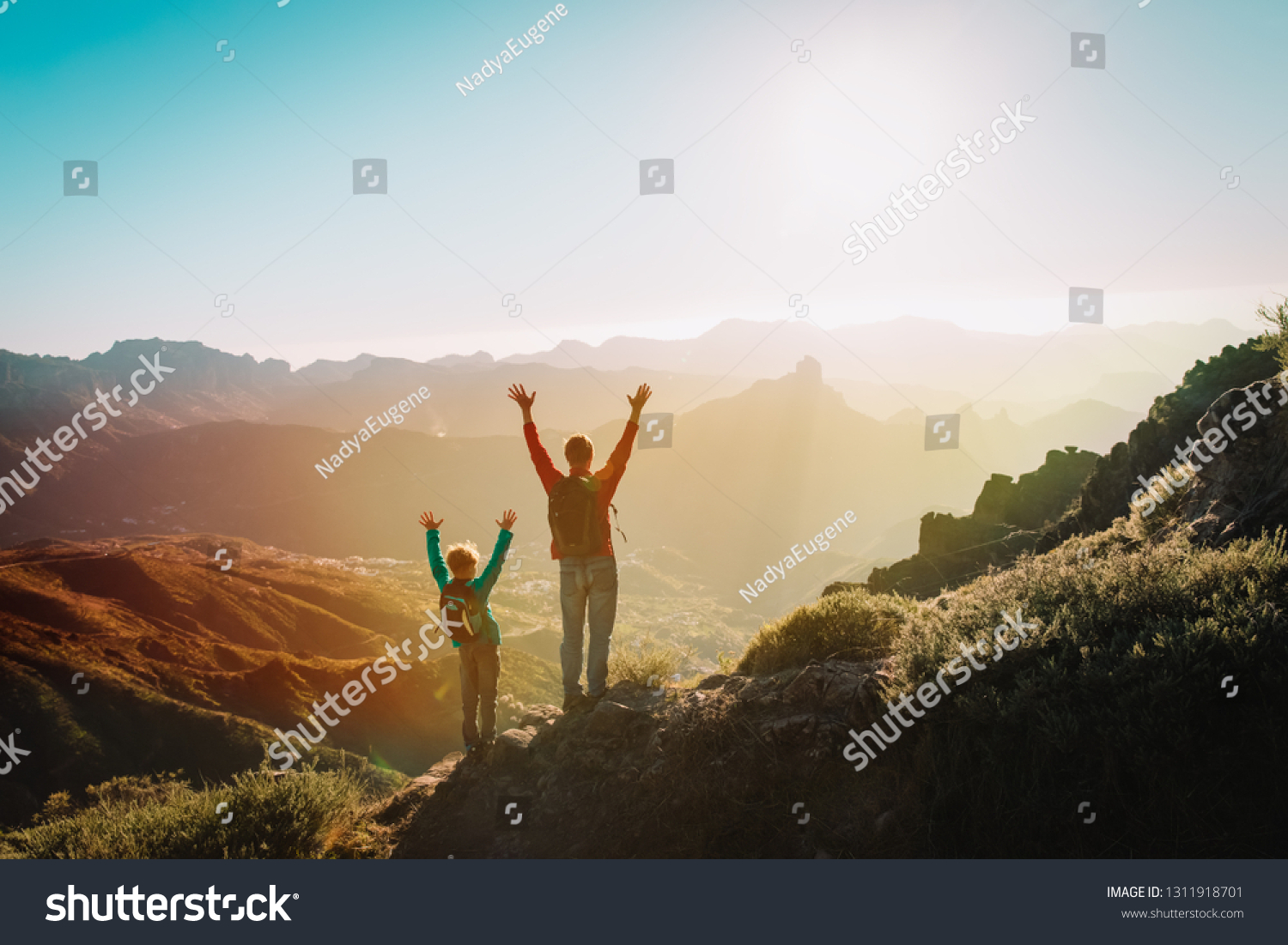 Father and son travel in sunset mountains, family hiking in nature #1311918701
