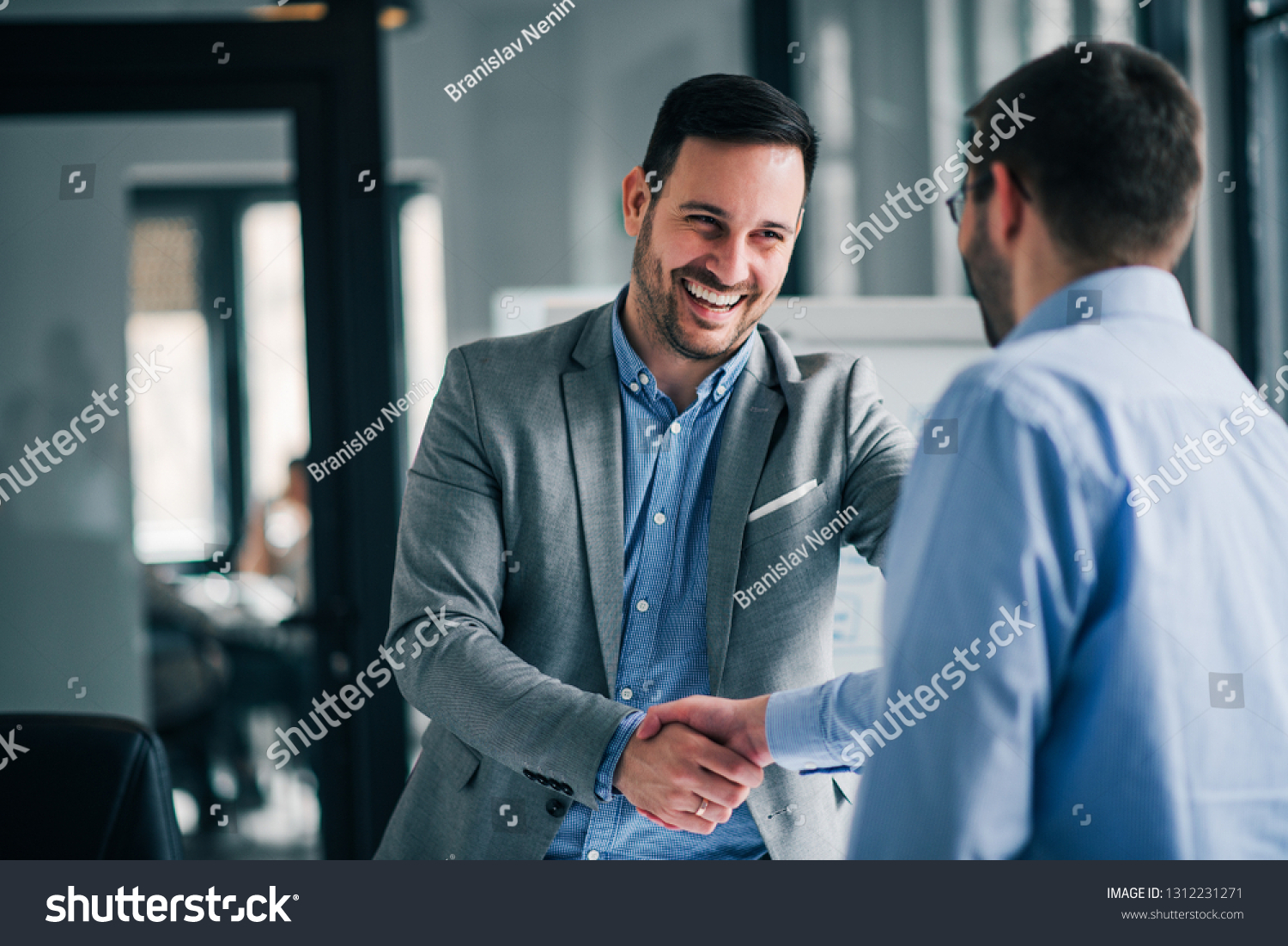 Portrait of cheerful young manager handshake with new employee.  #1312231271