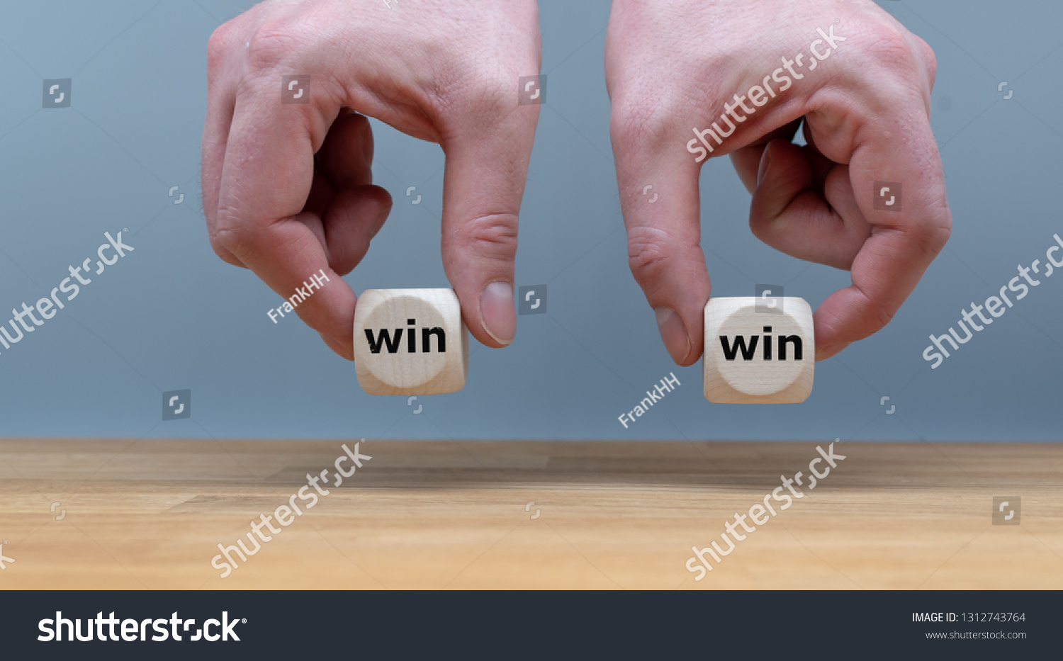 Symbol for a win win situation. Hands are holding two dice with the words "win" and "win" in front of a grey background. #1312743764