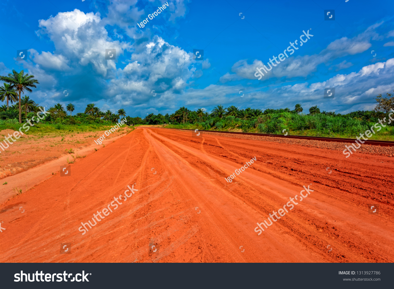 Typical red soils unpaved rough countryside road along railway track in Guinea, West Africa. #1313927786