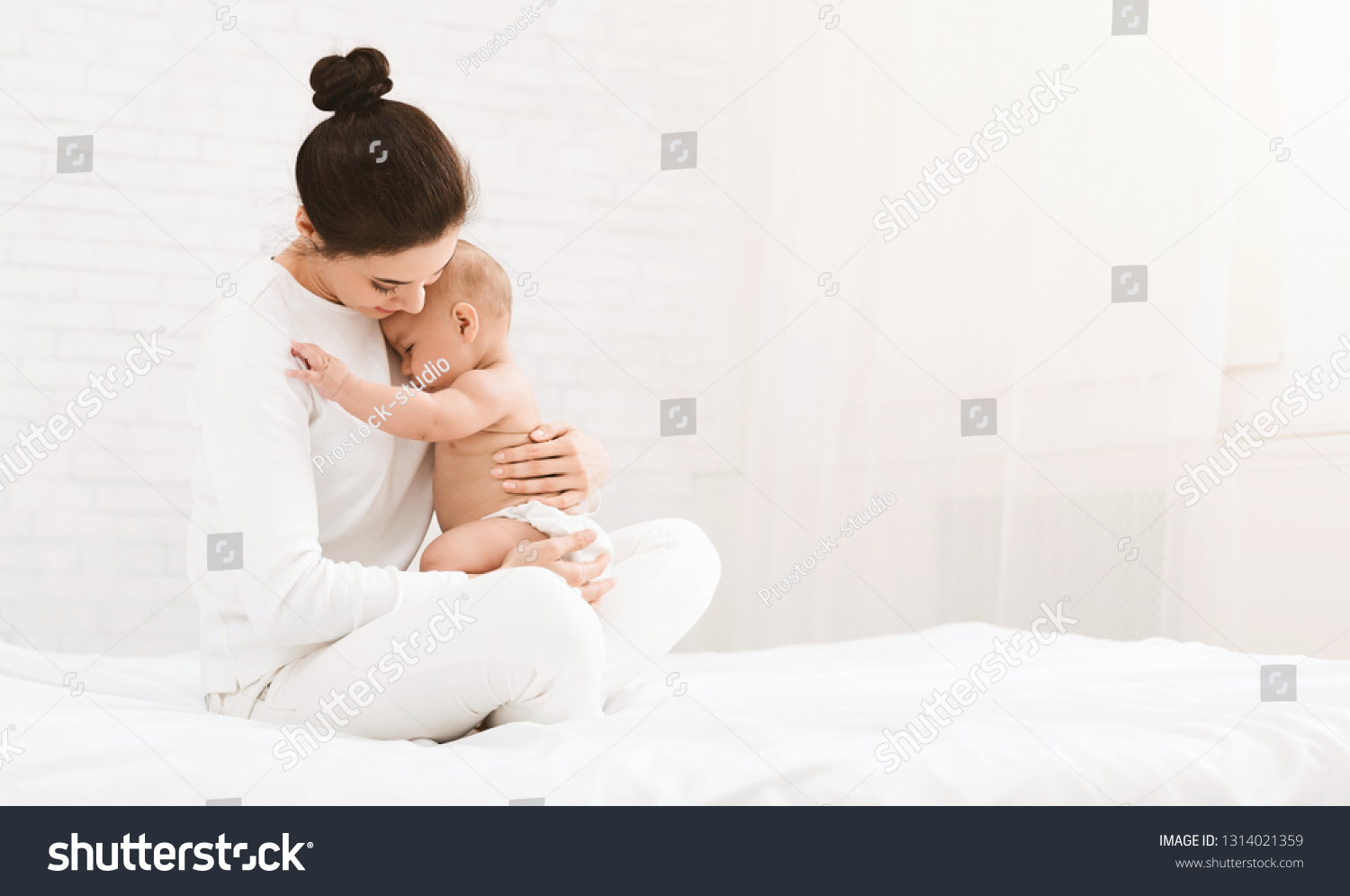 Young mother holding her newborn child, lulling baby in bed, copy space #1314021359