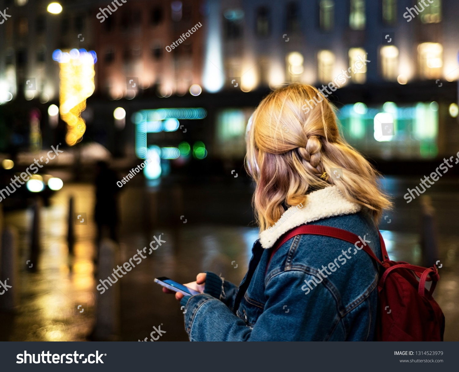 Young girl on the street with a mobile phone in his hands. View from the back. #1314523979