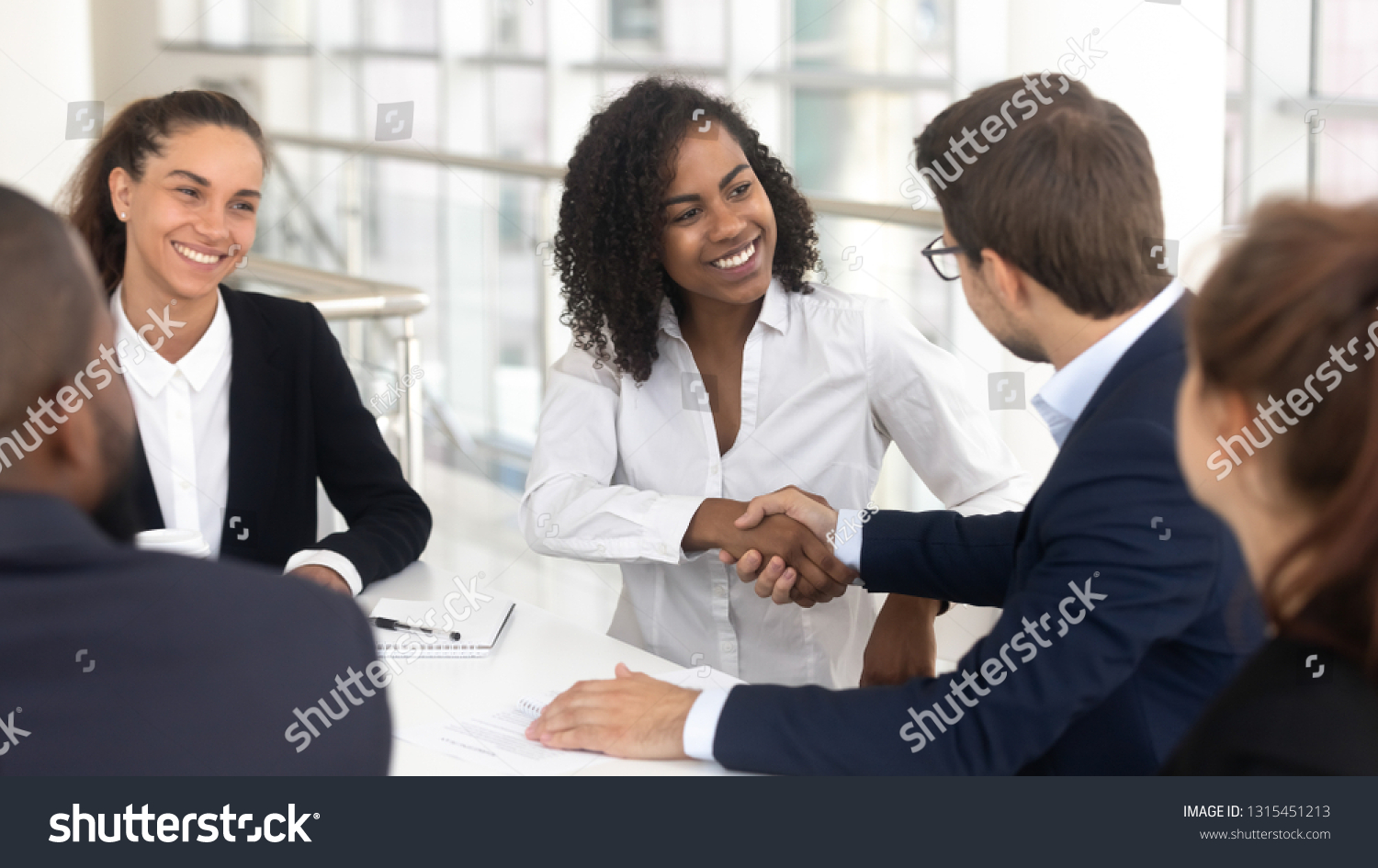 Multiracial businessman businesswoman shake hands starting collaboration at group negotiations, positive people gathered at modern office boardroom, partnership teamwork and business etiquette concept #1315451213