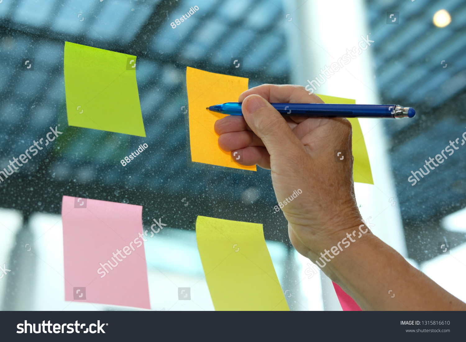 Businessman write on adhesive notes on glass wall at workplace. Sticky note paper reminder schedule for discussing creative idea & business brainstorming #1315816610