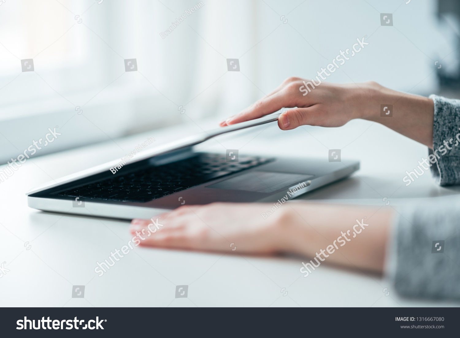 Close-up image of female hands open or close laptop on white table. #1316667080