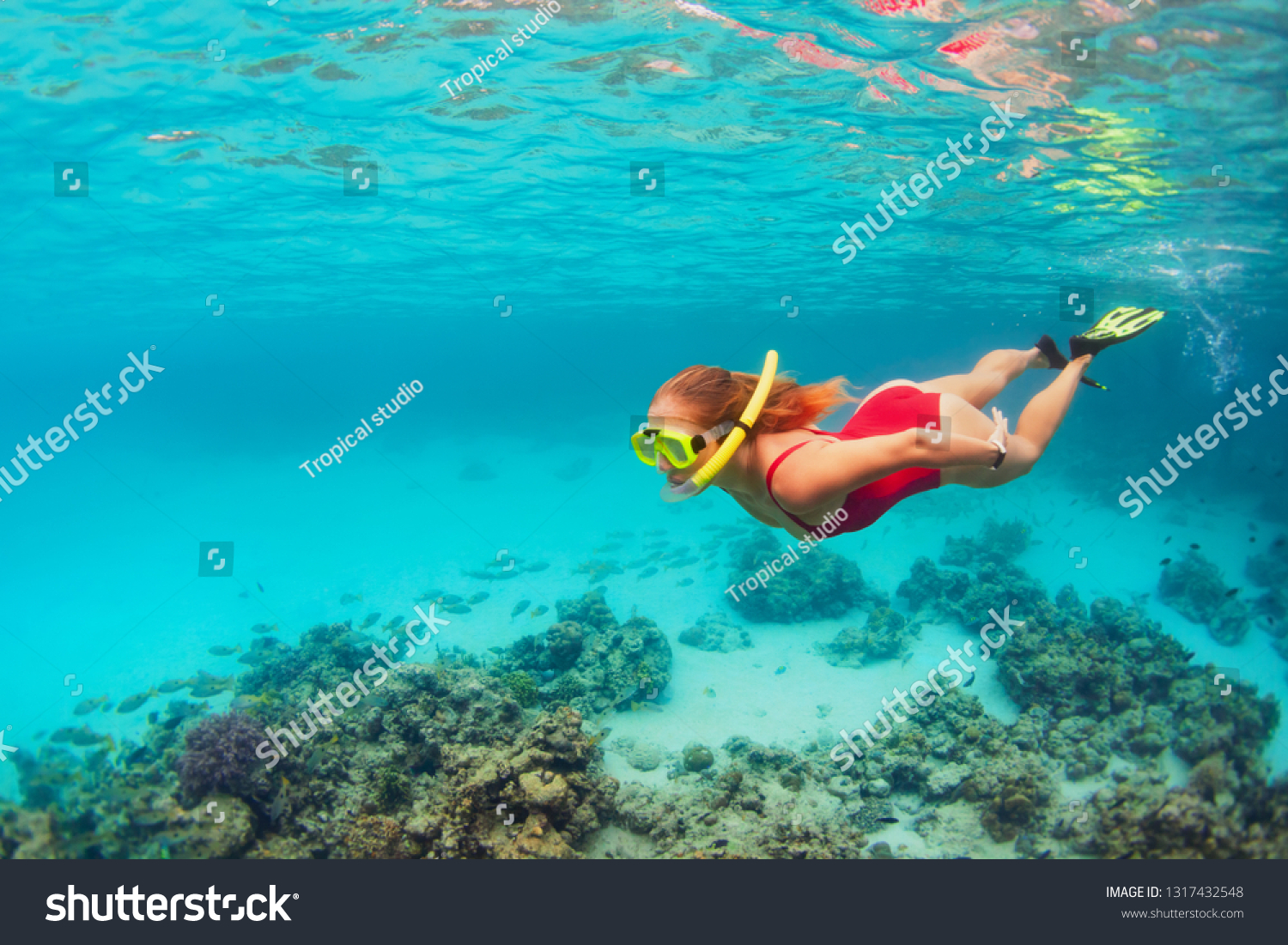 Young happy girl in snorkeling mask jump and dive underwater to see tropical fishes in coral reef sea pool. Travel activity, water sports, outdoor adventure, on family summer beach holiday with kids #1317432548