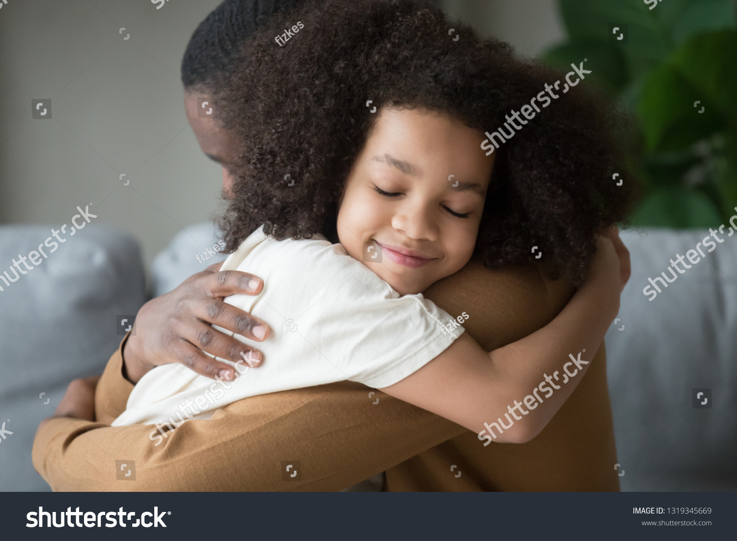 Cute funny mixed race child daughter embracing black father holding tight feeling love connection affection concept, happy african family dad and little kid girl hugging cuddling bonding at home #1319345669