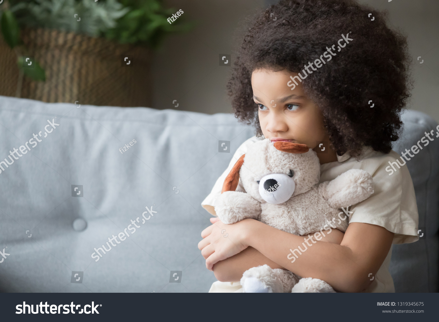 Upset lonely bullied little african american kid girl holding teddy bear looking away feels abandoned abused, sad alone preschool mixed race child orphan hugging stuffed toy, charity adoption concept #1319345675