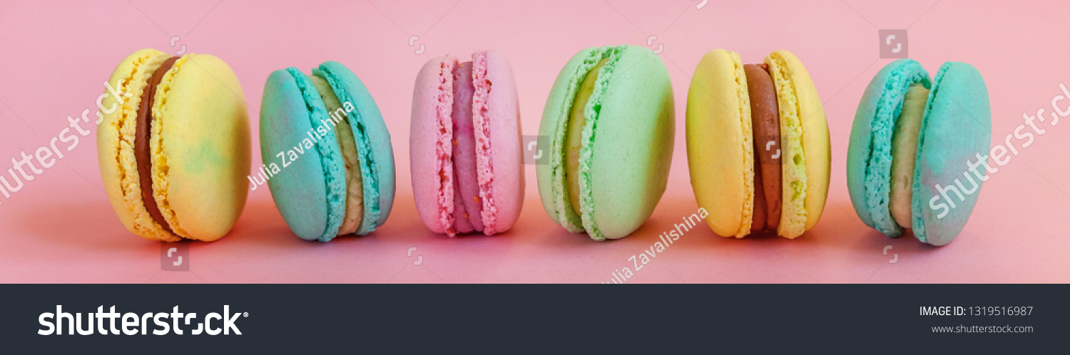 Sweet almond colorful unicorn pink blue yellow green macaron or macaroon dessert cake isolated on trendy pink pastel background. French sweet cookie. Minimal food bakery concept. Banner #1319516987