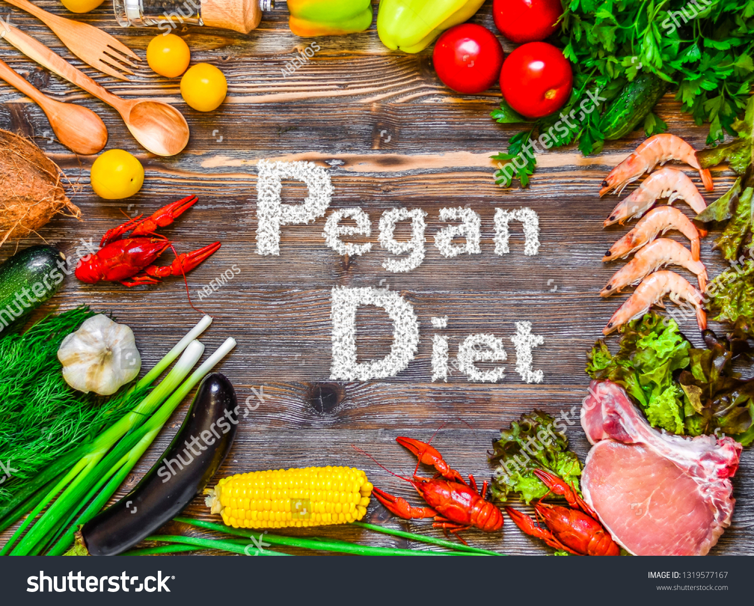A top view of raw vegetables and meats with the text: Pegan Diet displayed on the wooden table in the middle. Pegan diet is a combination of vegan and paleo diets nutrients. #1319577167