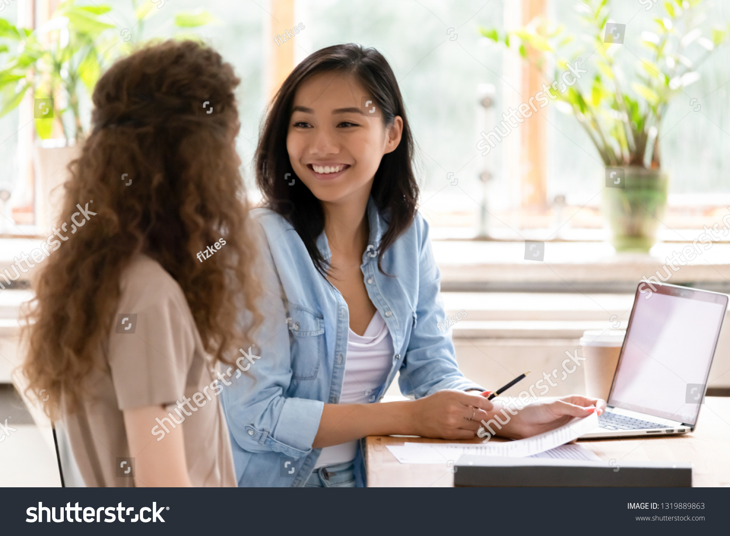Smiling asian hr insurer advisor meeting applicant at job interview consulting client about contract offer giving advice, happy diverse girls colleagues interns students discussing paperwork together #1319889863