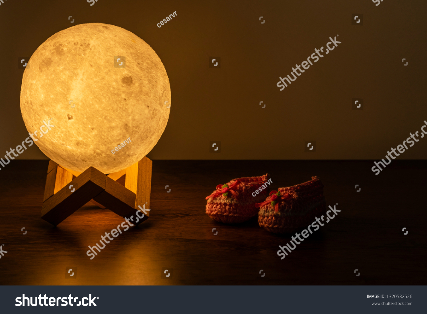 moon lamp and baby slipper on wooden table #1320532526