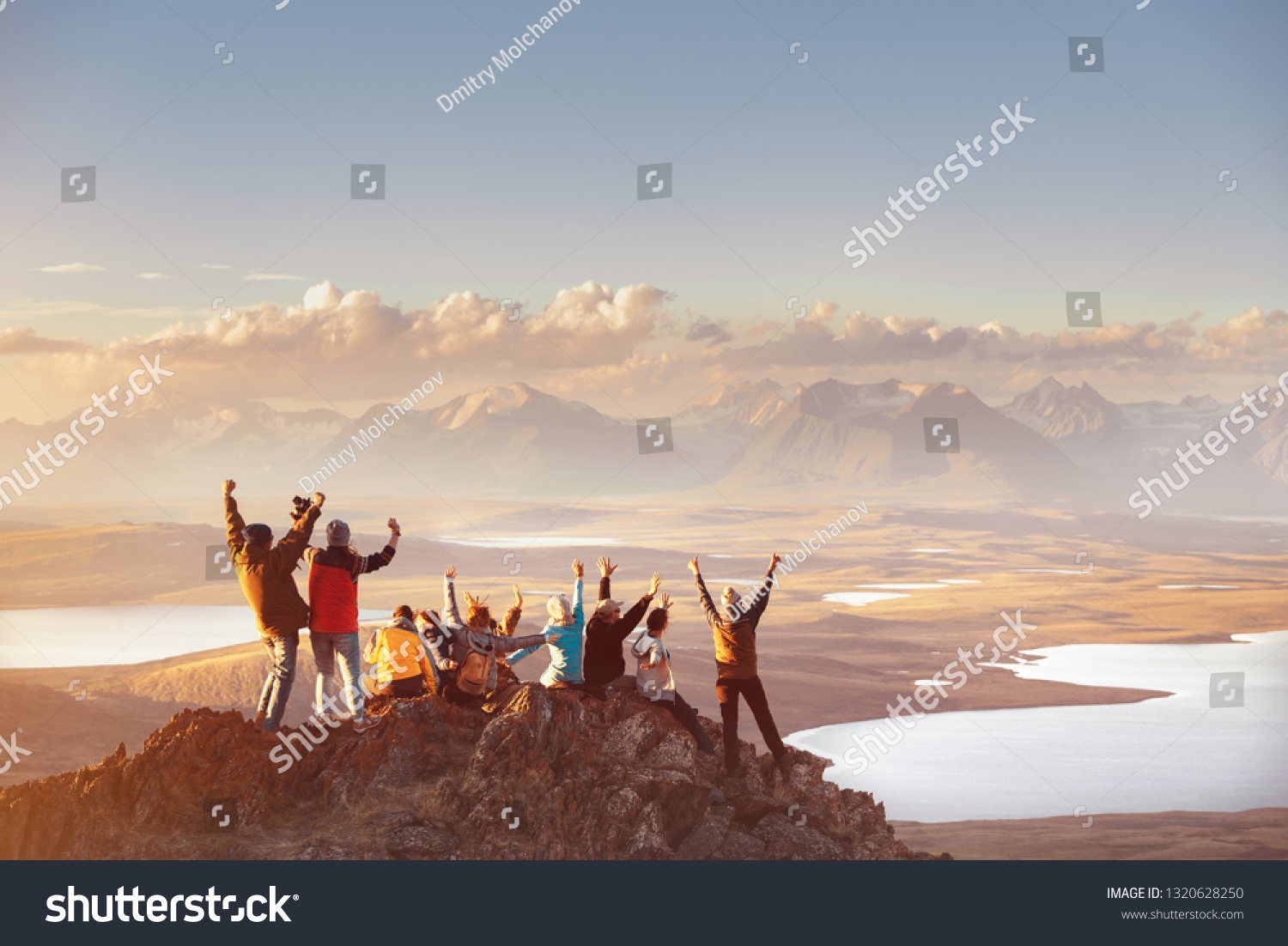 Large group of happy friends is having fun on mountain top and looks at mountain's valley. Adventure or travel concept #1320628250