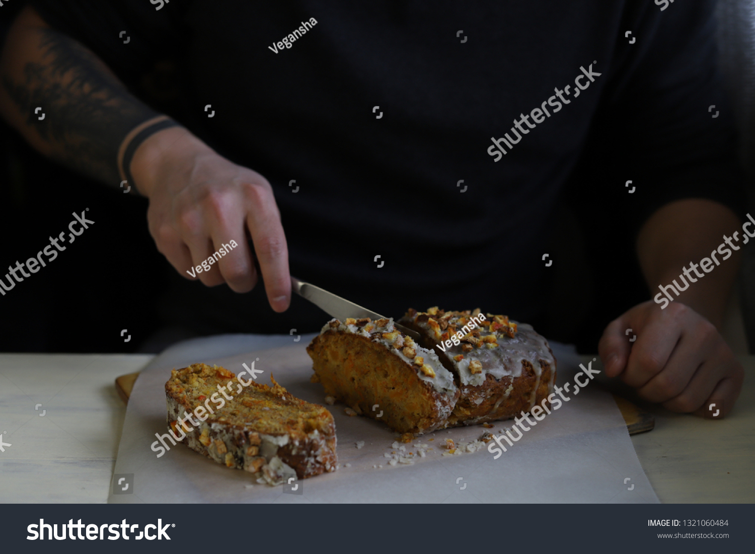 A tattooed man cuts apricot vegan cake  #1321060484