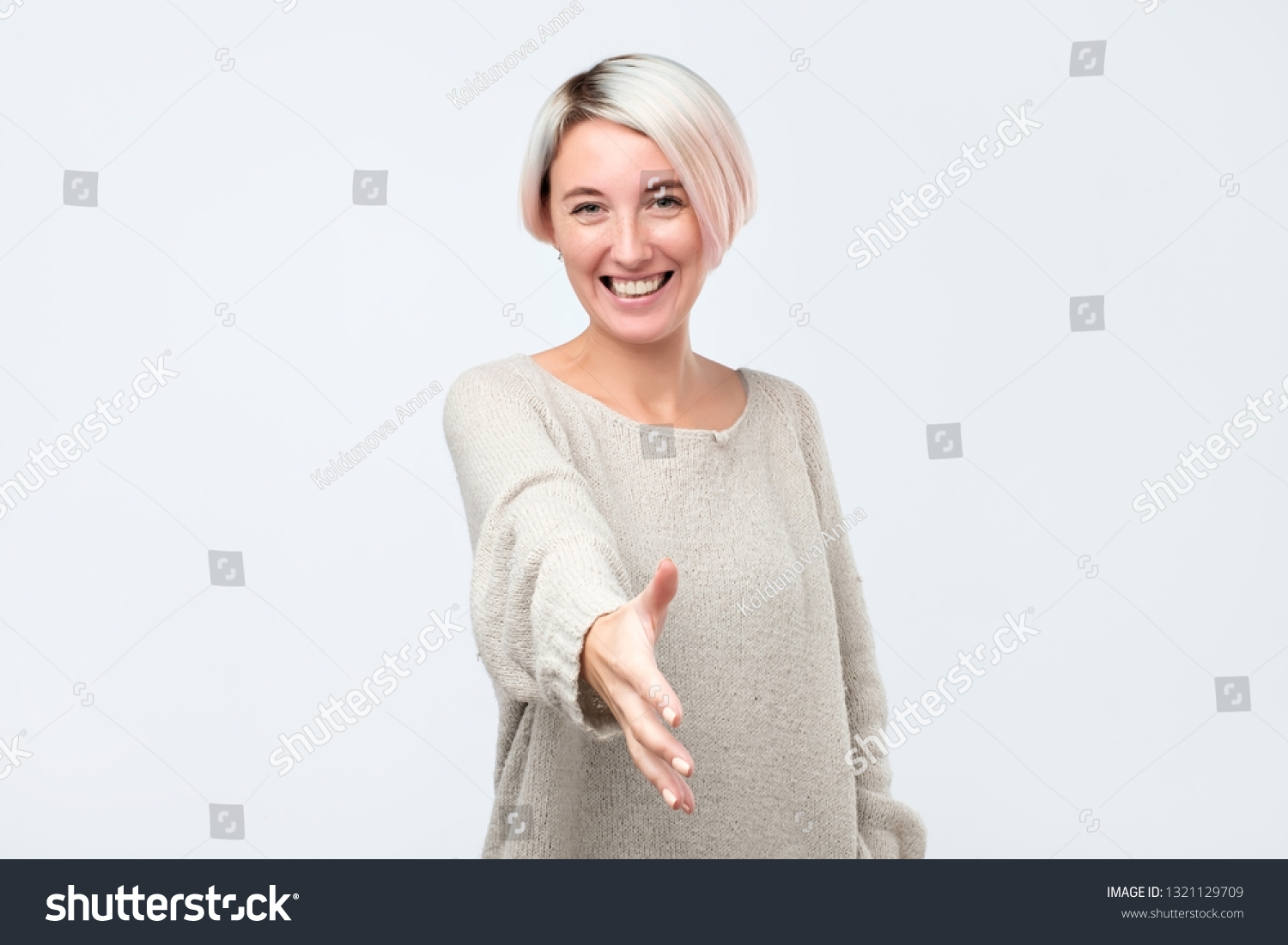 Beautiful european woman stretches hand in front, greets somebody, being glad to meet with friend. I am glad to see you, first meet with your coworker. #1321129709