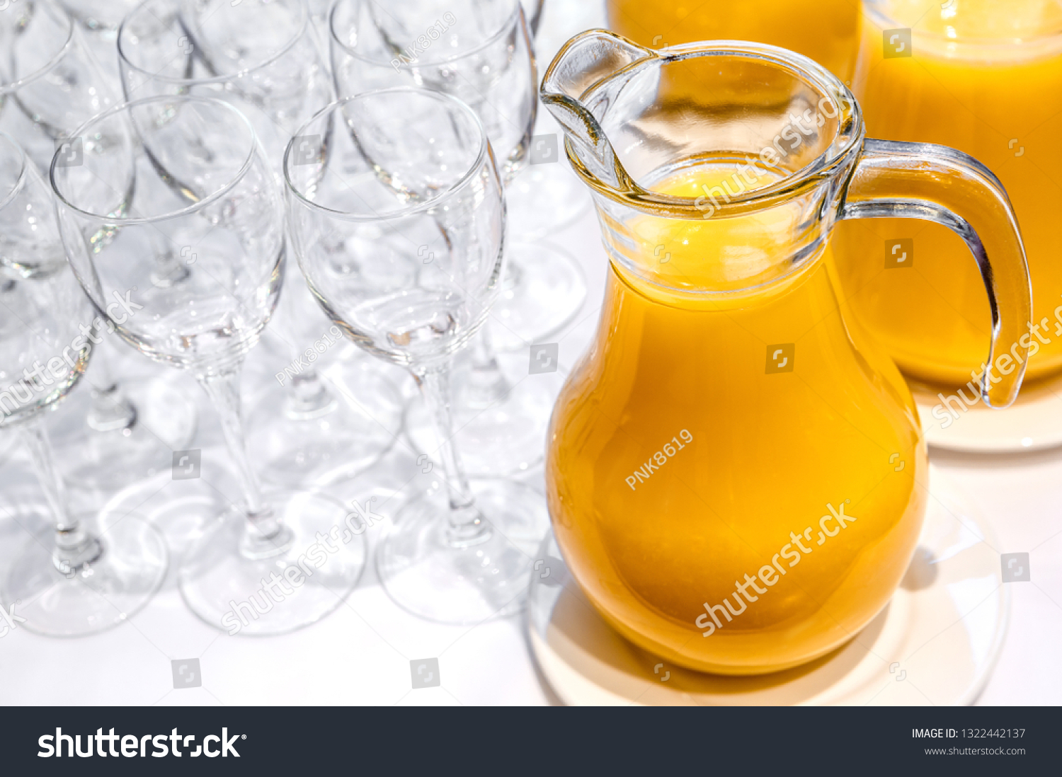 Jugs with freshly squeezed orange juice and clean transparent glasses #1322442137
