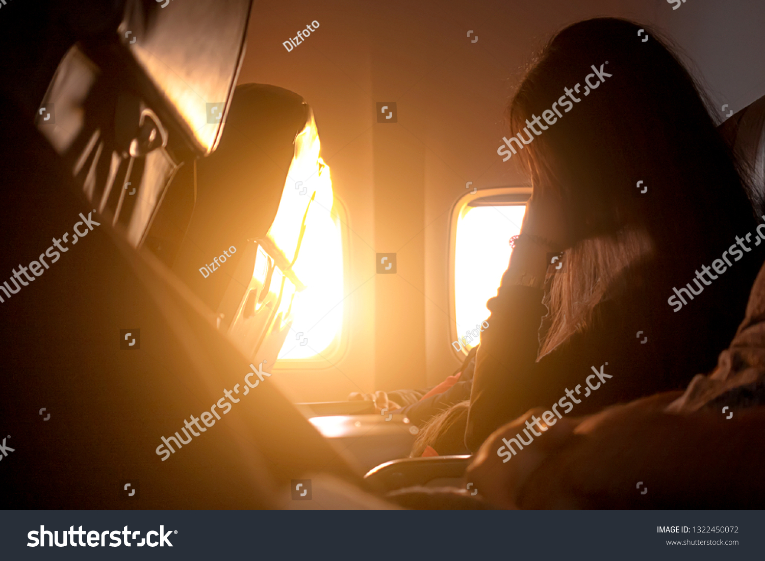 The girl travels in an airplane sitting near the window in the background of the sunset #1322450072