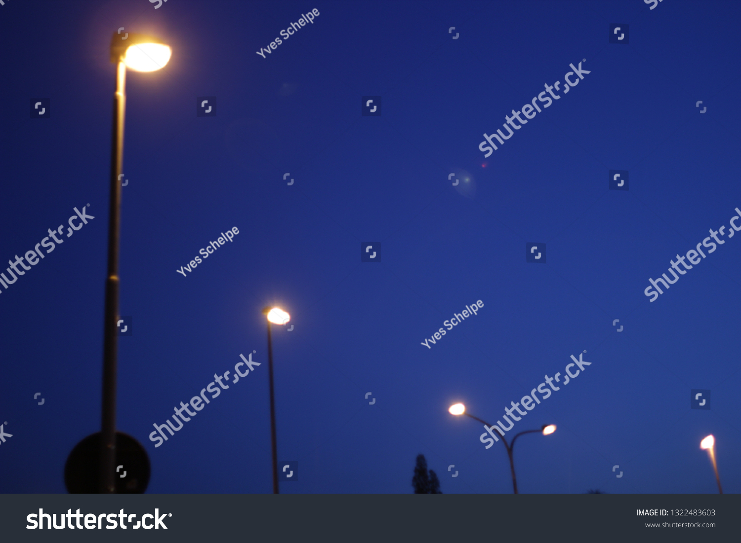 Streetlamps shining at a clear blue night sky #1322483603