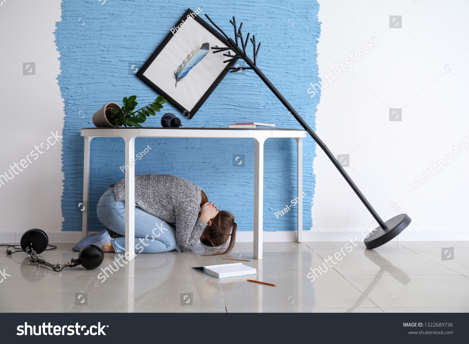 Young woman hiding under table during earthquake #1322689736