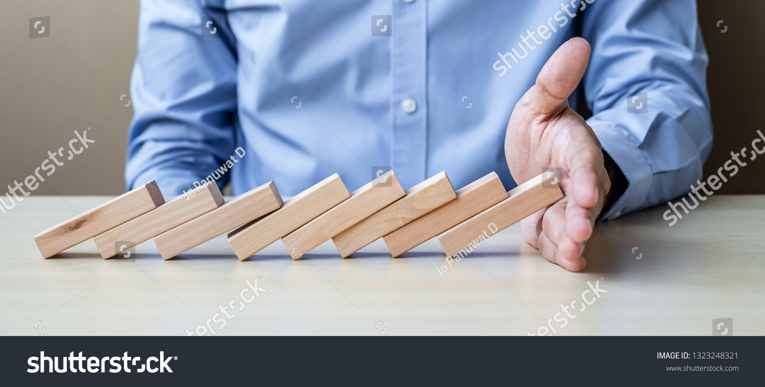 Businessman hand Stopping Falling wooden Blocks or Dominoes. Business, Risk Management, Solution, Insurance and strategy Concepts #1323248321