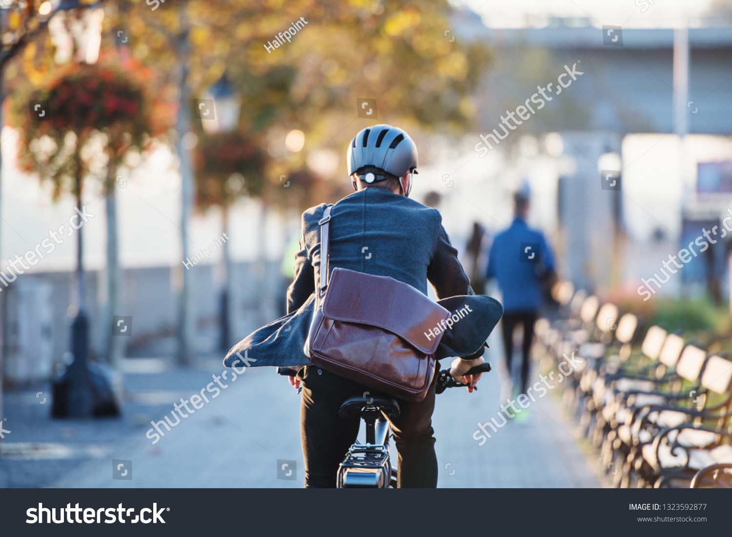 A rear view of businessman commuter with electric bicycle traveling to work in city. #1323592877