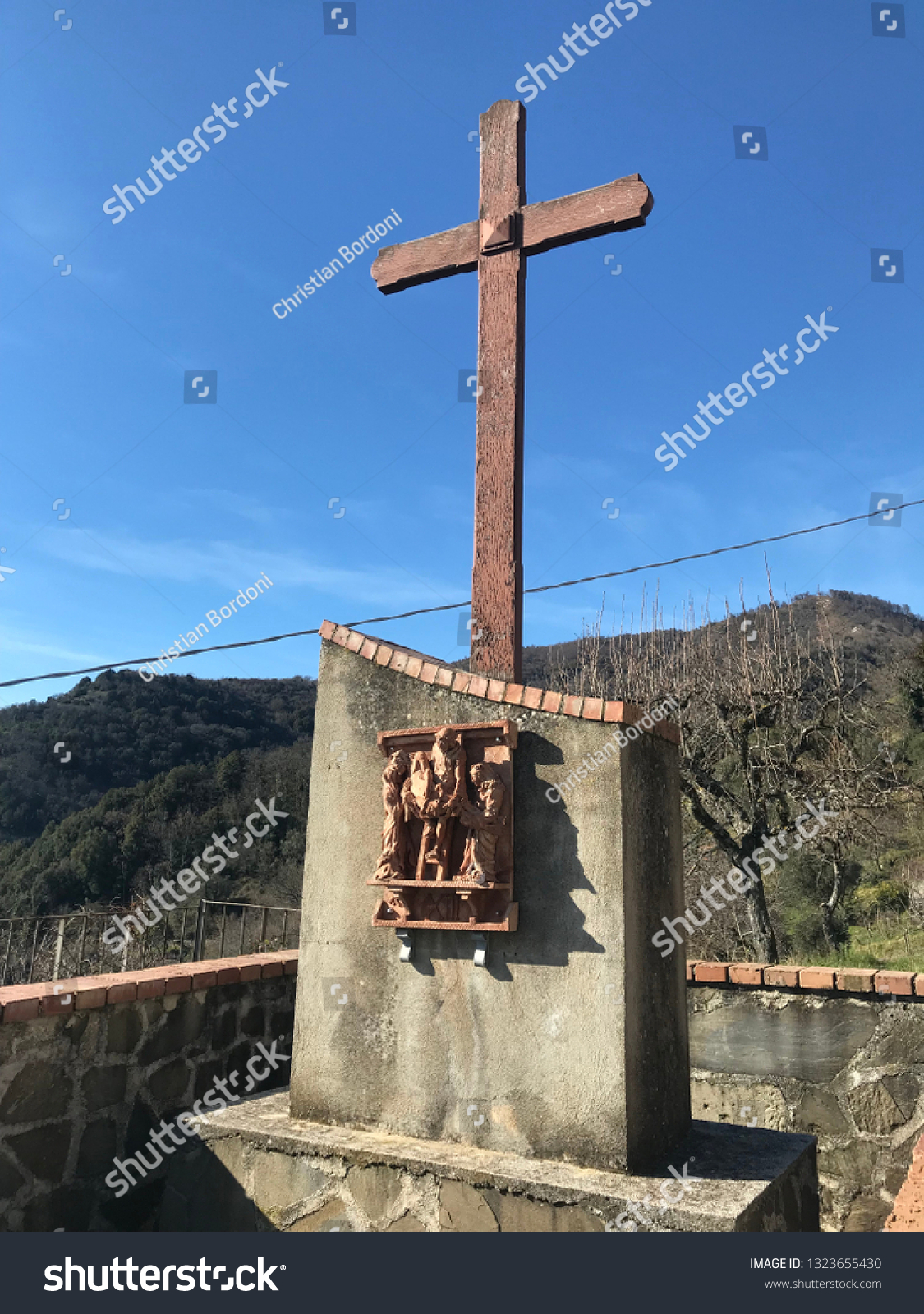 Old rusty metal cross against a blue sky with white clouds #1323655430