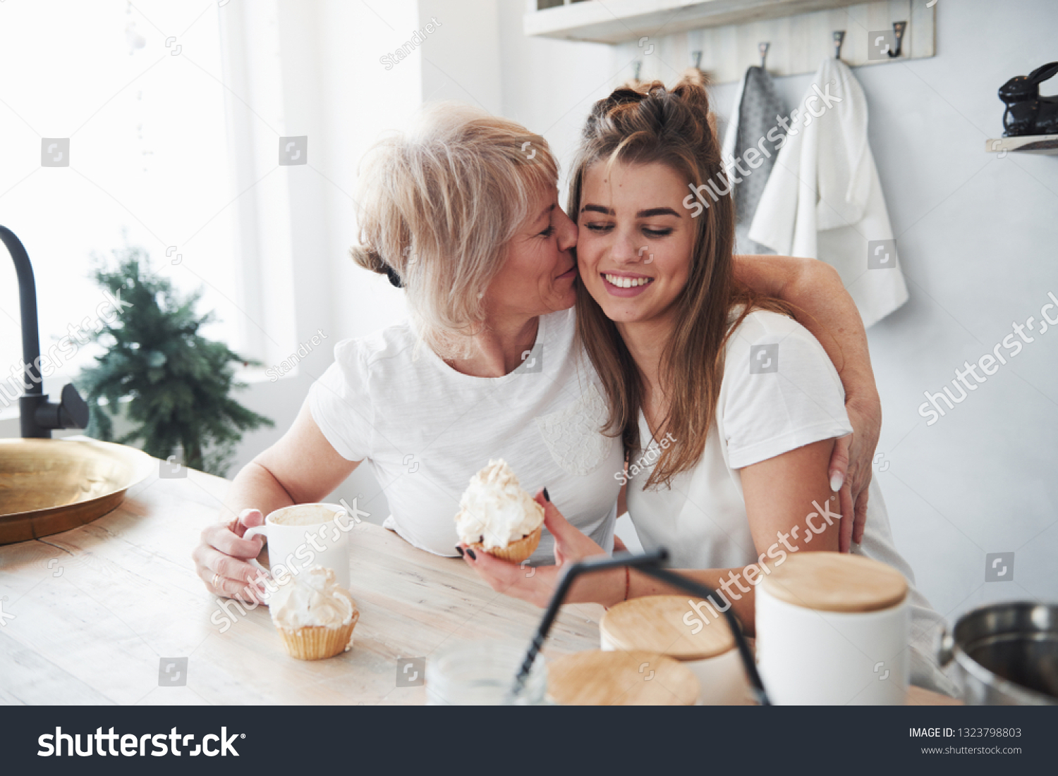 Cute kiss. Mother and daughter having good time in the kitchen. #1323798803