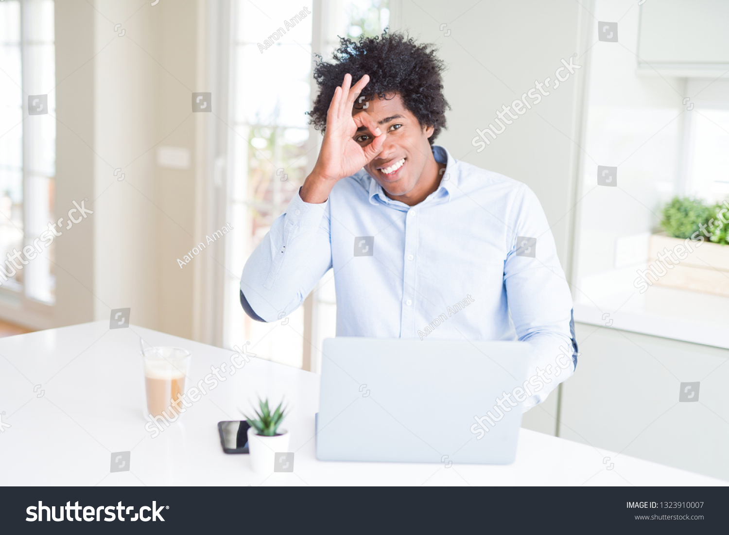 African American business man working using laptop with happy face smiling doing ok sign with hand on eye looking through fingers #1323910007