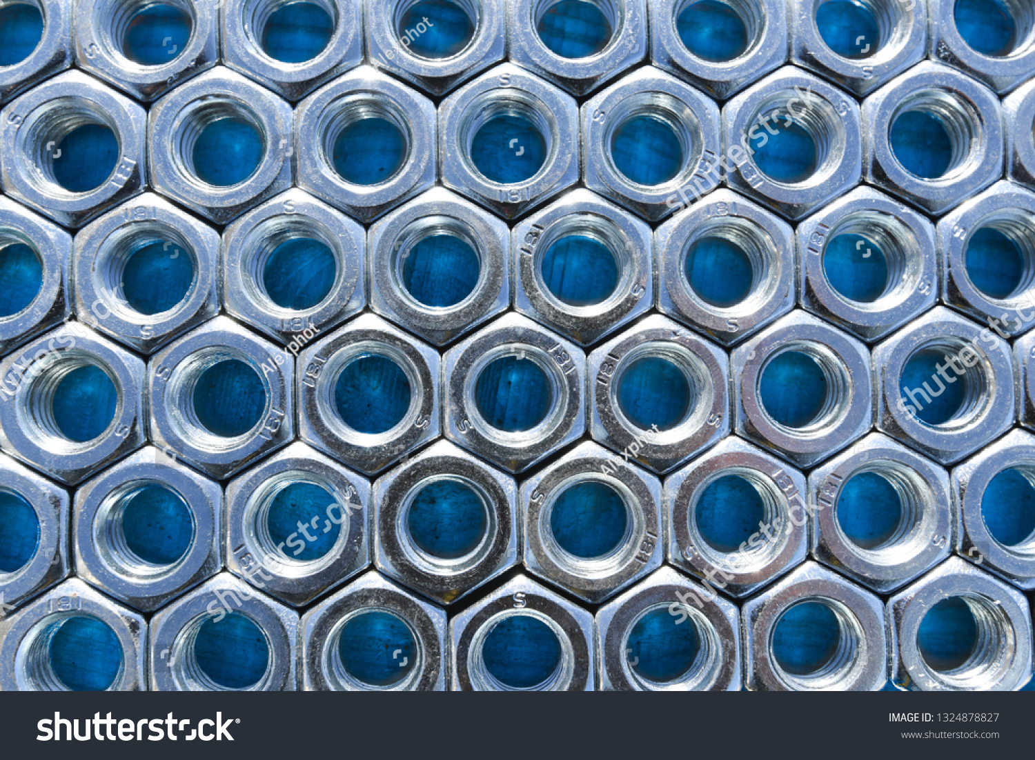 Metal nuts on blue background. Abstract industry background. Natural photo. #1324878827