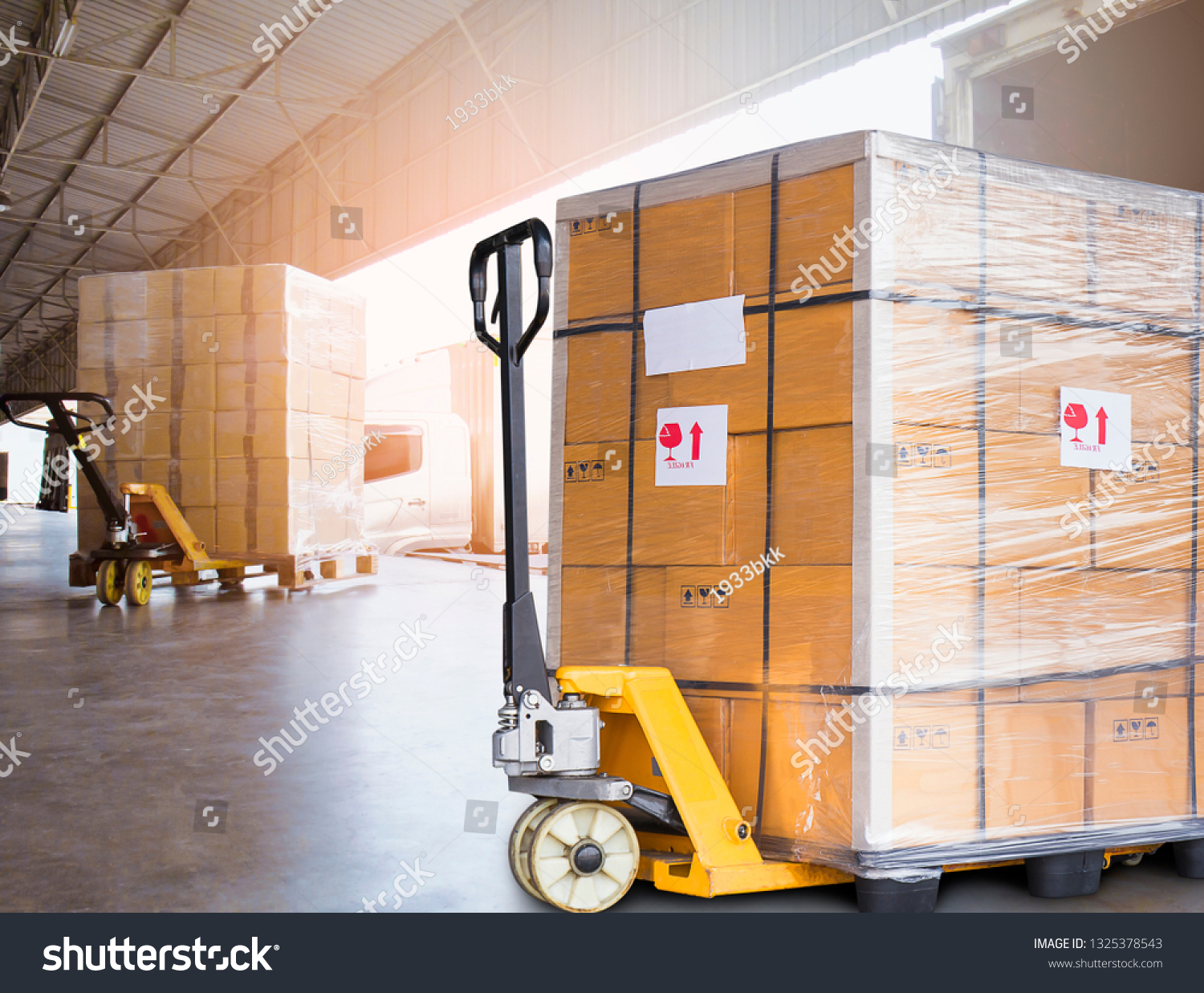 Large cargo shipment pallets. Hand pallet truck with stacked cardboard boxes wrapping plastic on pallet at warehouse dock. warehouse industry freight, logistics and transport.  #1325378543
