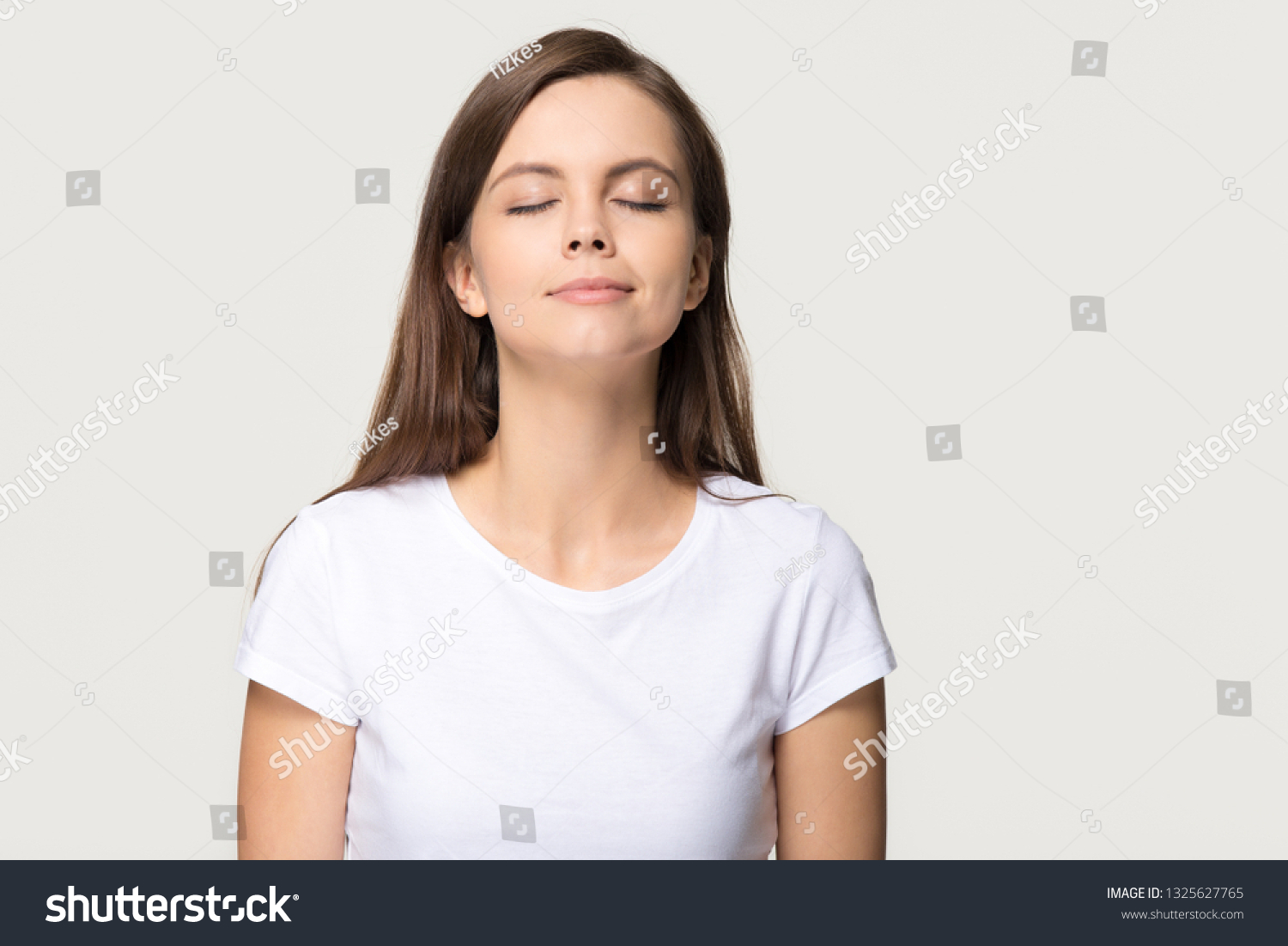 Happy calm teen girl enjoying good smell or pleasant fragrance, serene mindful young woman taking deep breath feel no stress free inhaling fresh air relaxing isolated on white grey studio background #1325627765