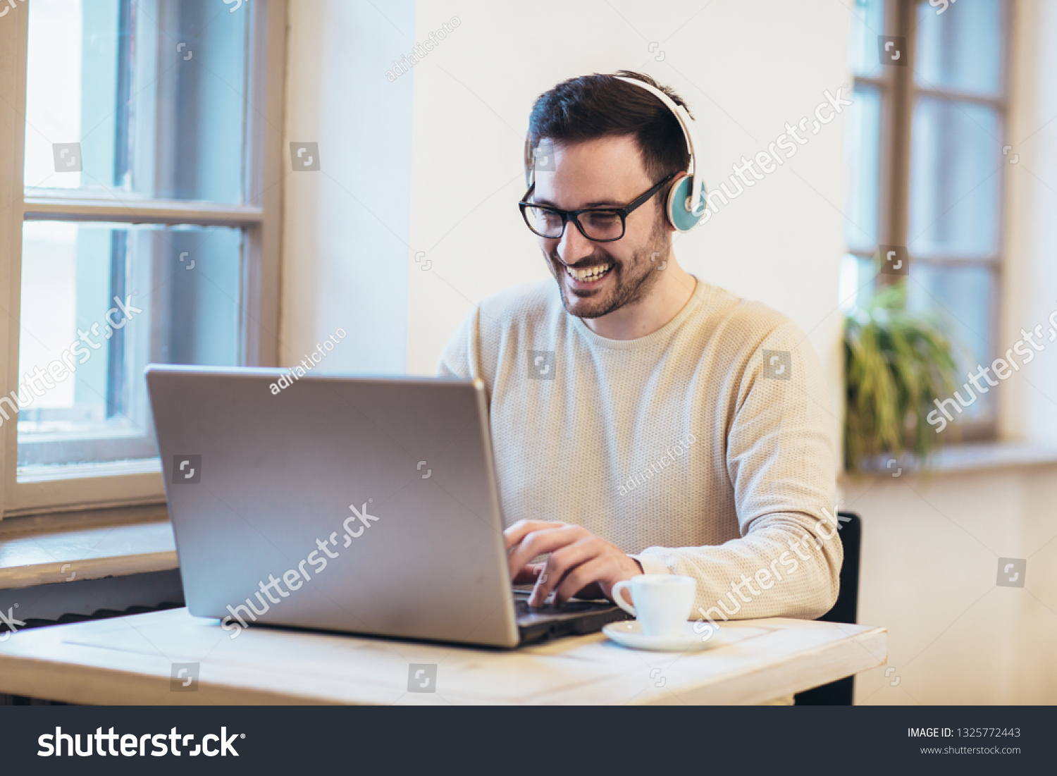 Man in front of laptop computer with headset #1325772443