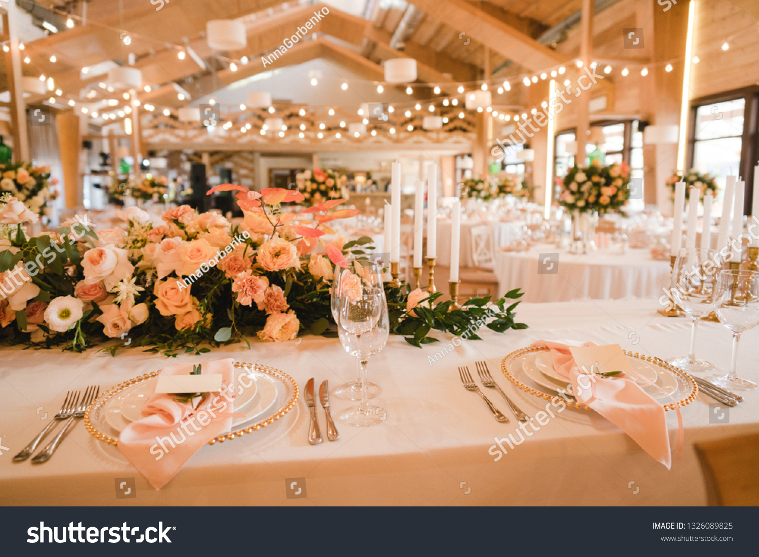Coziness and style. Modern event design. Table setting at wedding reception. Floral compositions with beautiful flowers and greenery, candles, laying and plates on decorated table. #1326089825